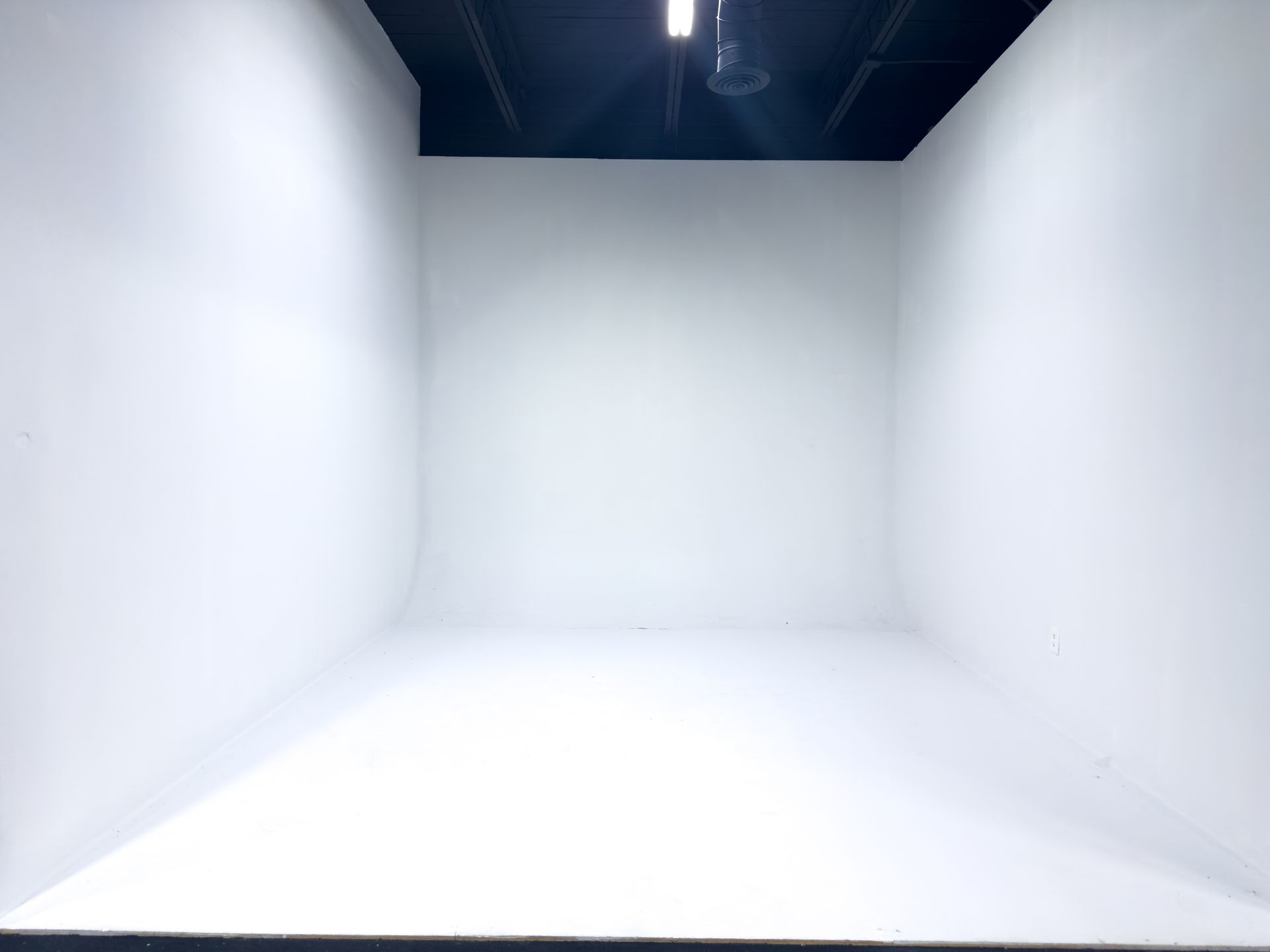 Empty white studio with seamless walls and overhead black ceiling rigging