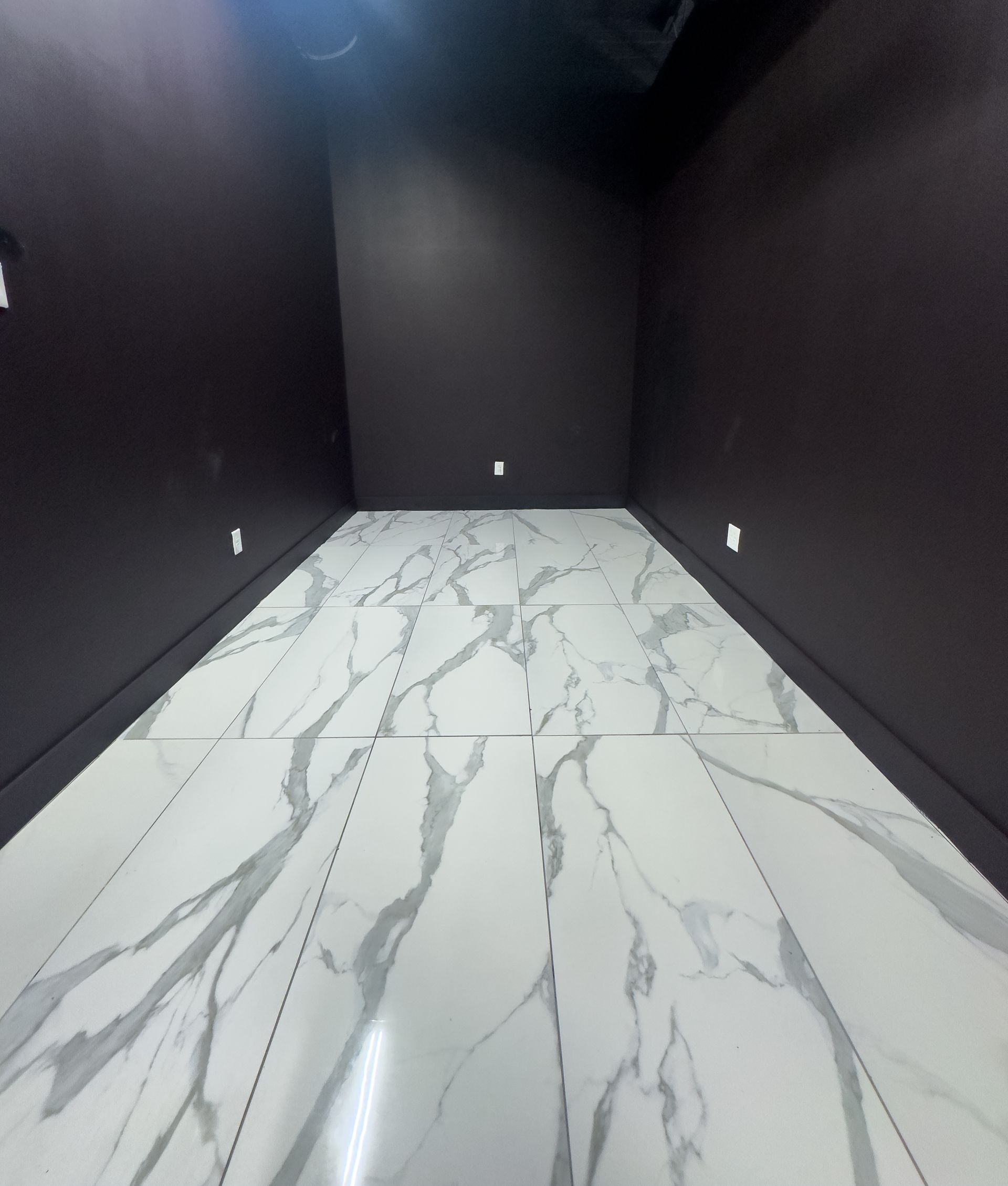 Empty modern room with dark walls and white marble-pattern tile floor