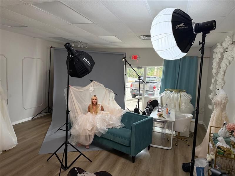 Portrait session in a bright studio with a model in a white dress, teal chair, and softbox lights
