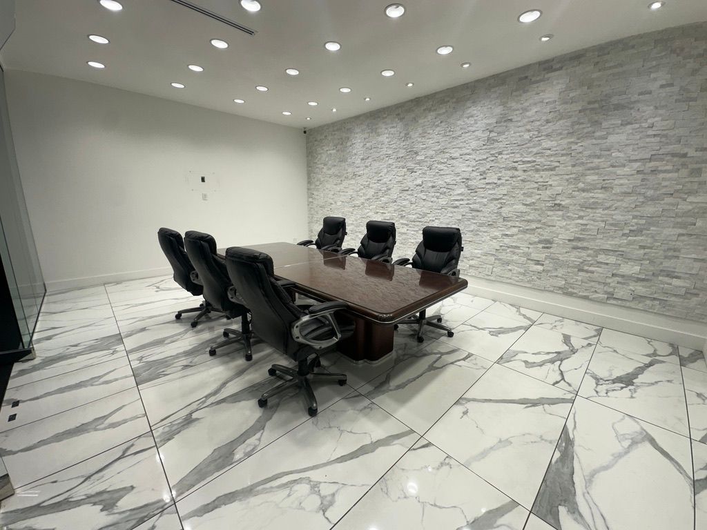 Modern conference room with long table, black chairs, marble floor, and textured gray accent wall