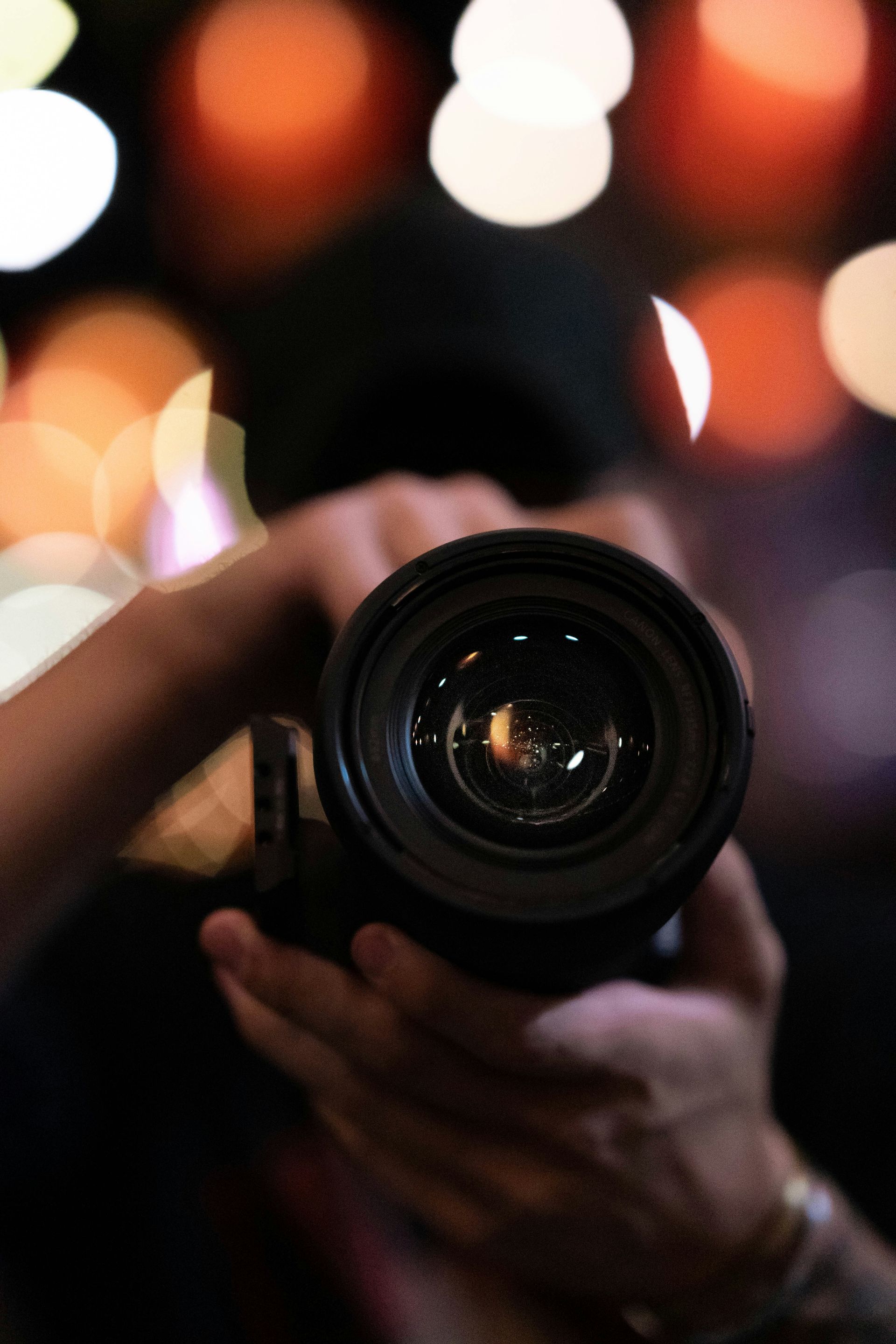 Person holding a camera with blurred colorful lights in the background