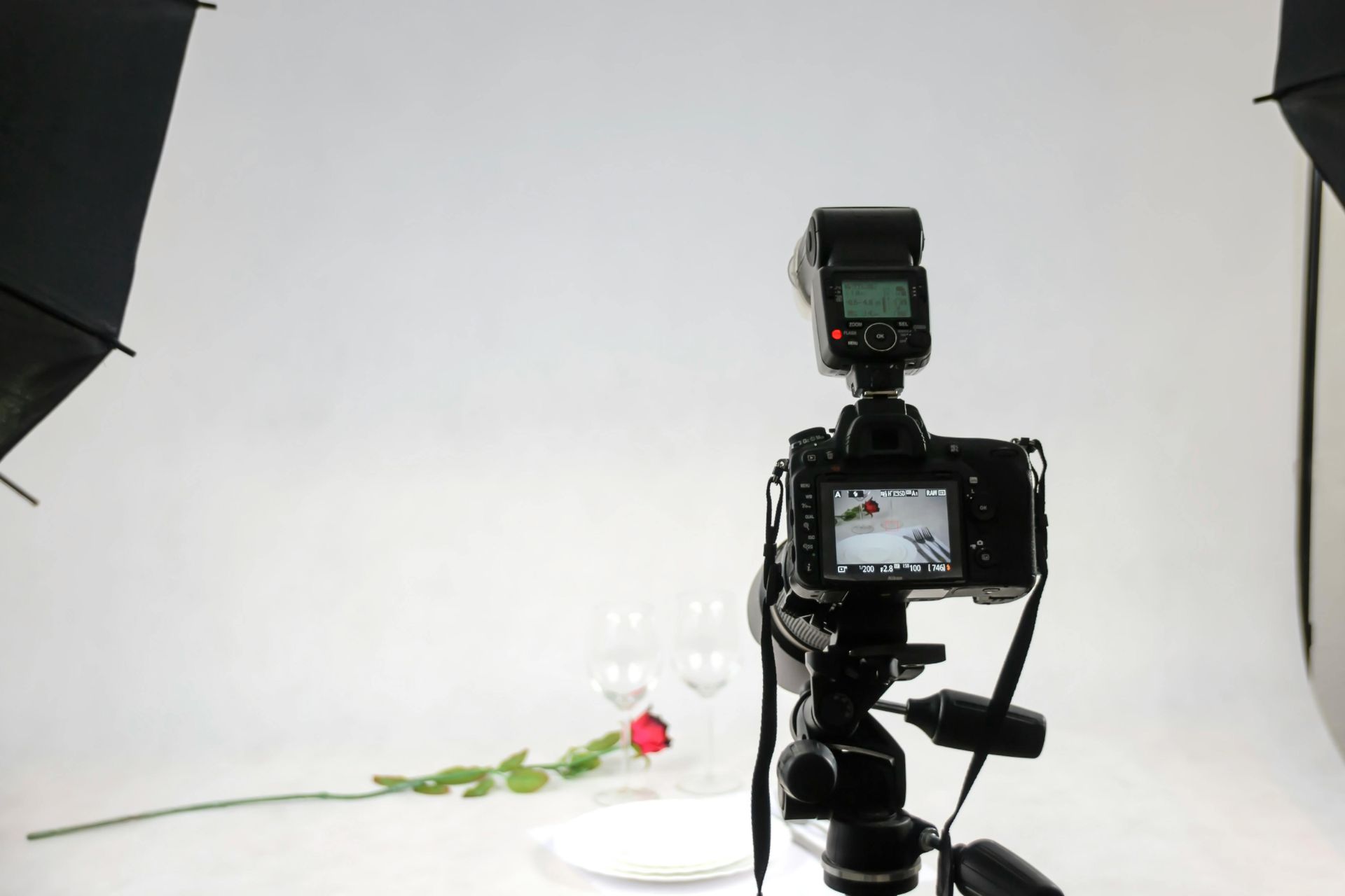 Studio camera setup photographing a white backdrop with a rose on the floor