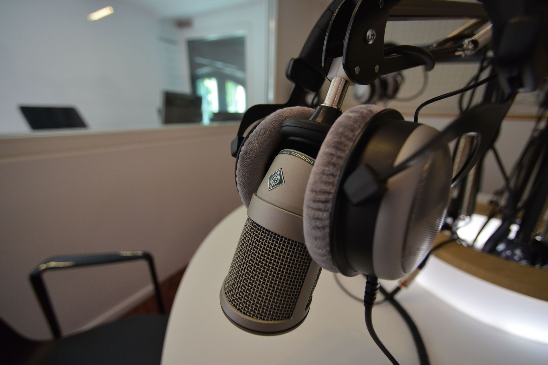 Microphone with headphones hanging on a stand in a recording studio setup