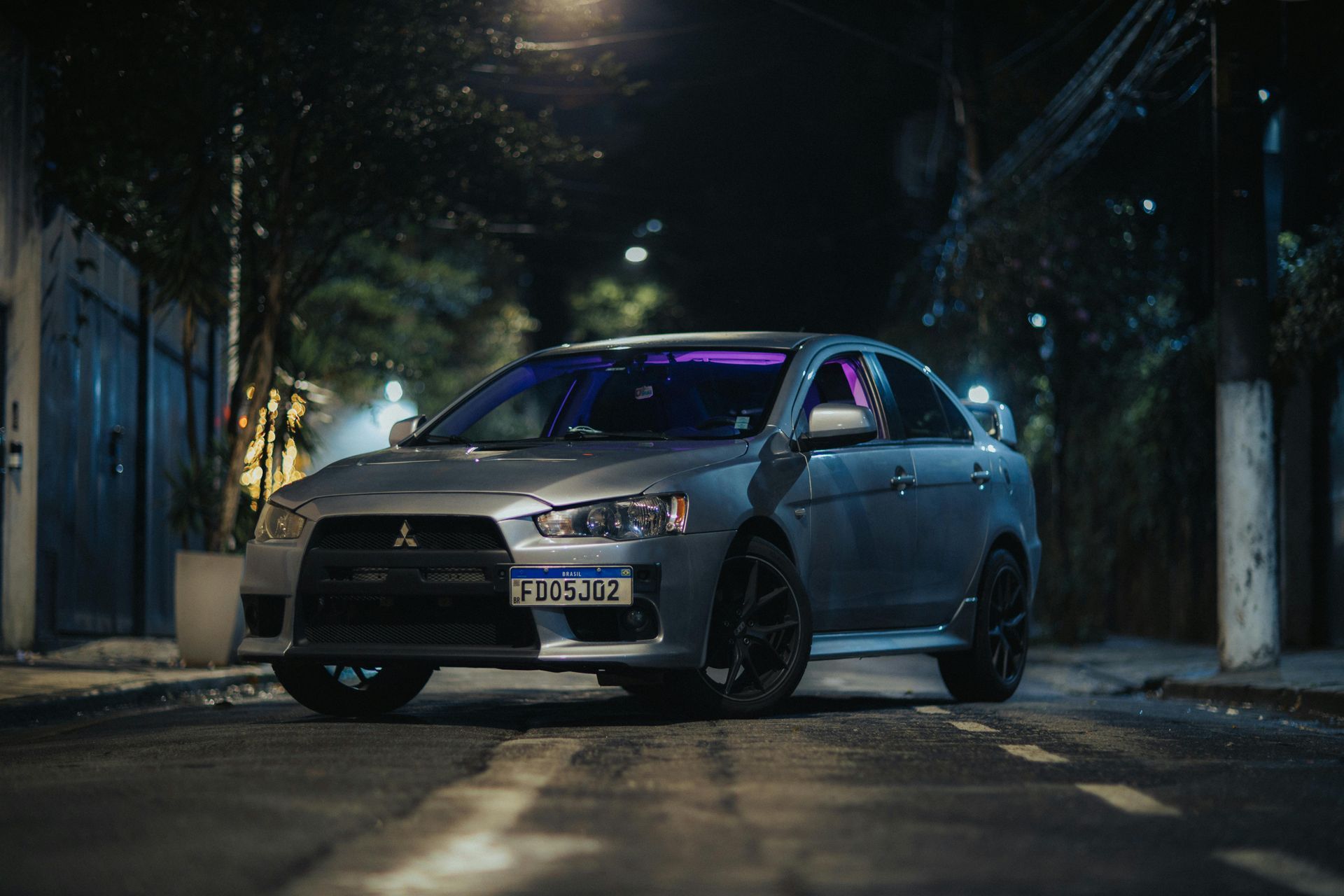 Blue car parked on a dimly lit street at night with purple interior lighting