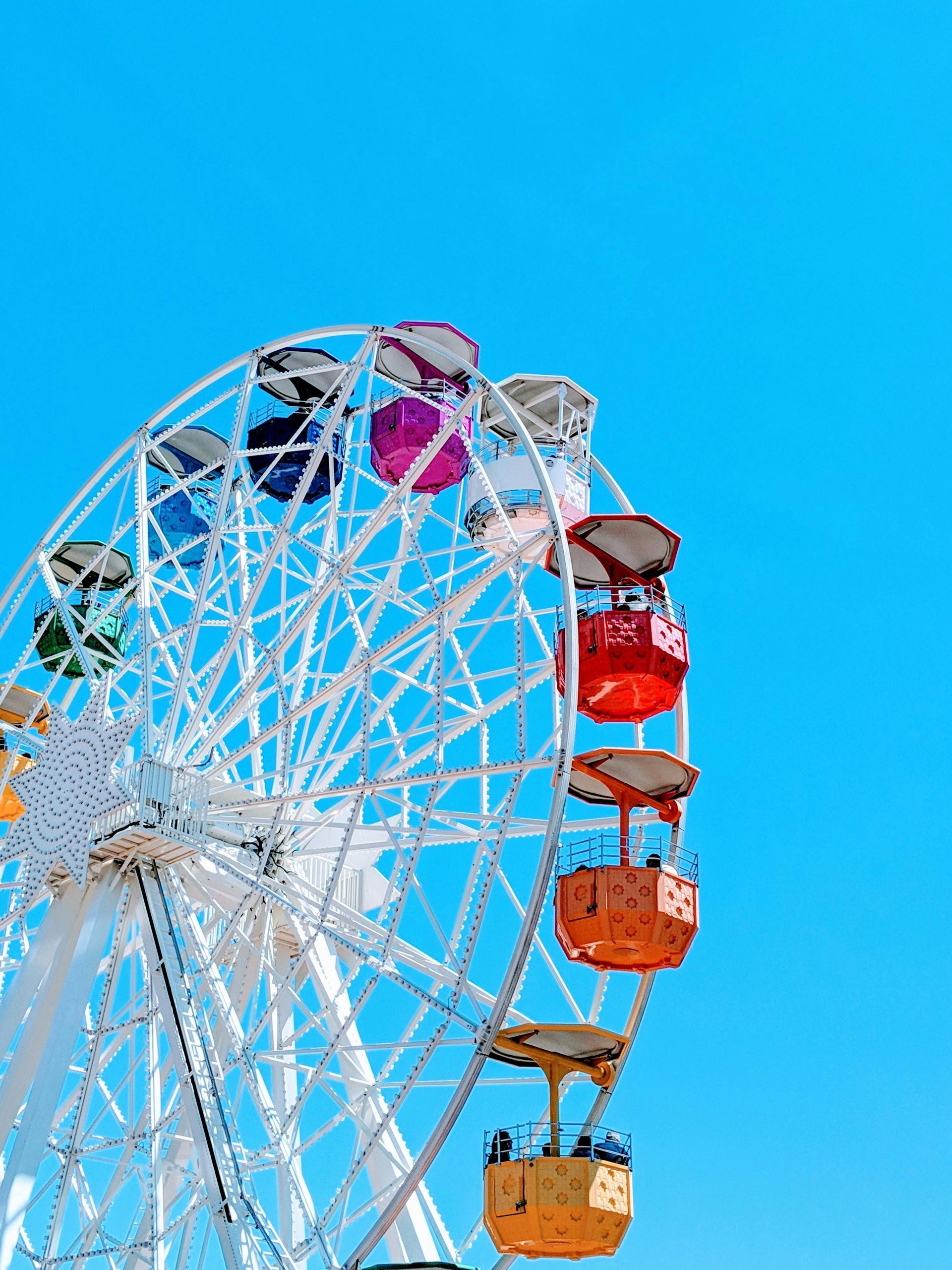 Ferris wheel with colorful gondolas against a bright blue sky
