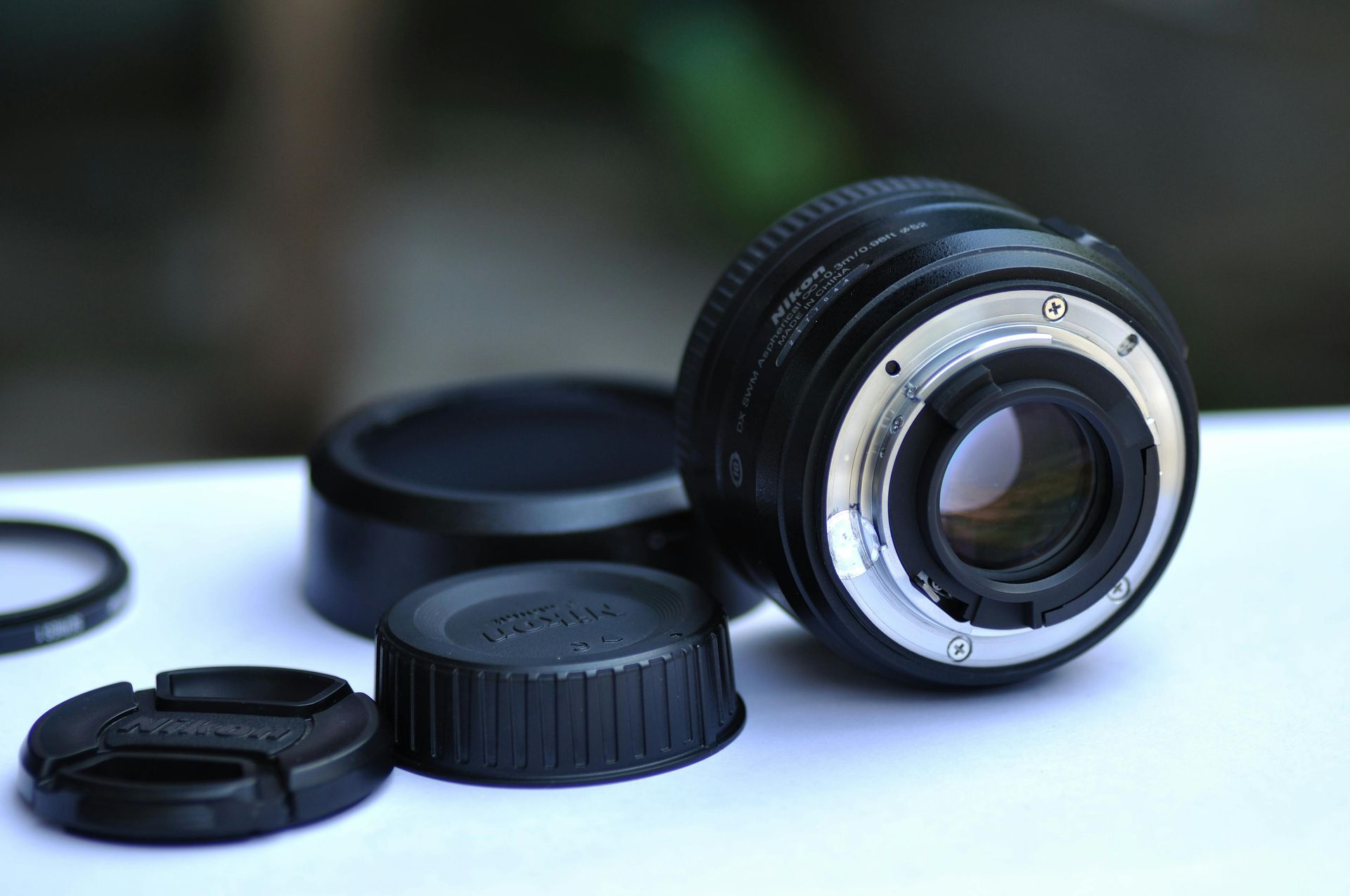 Camera lens with two caps on a white surface, in close-up.