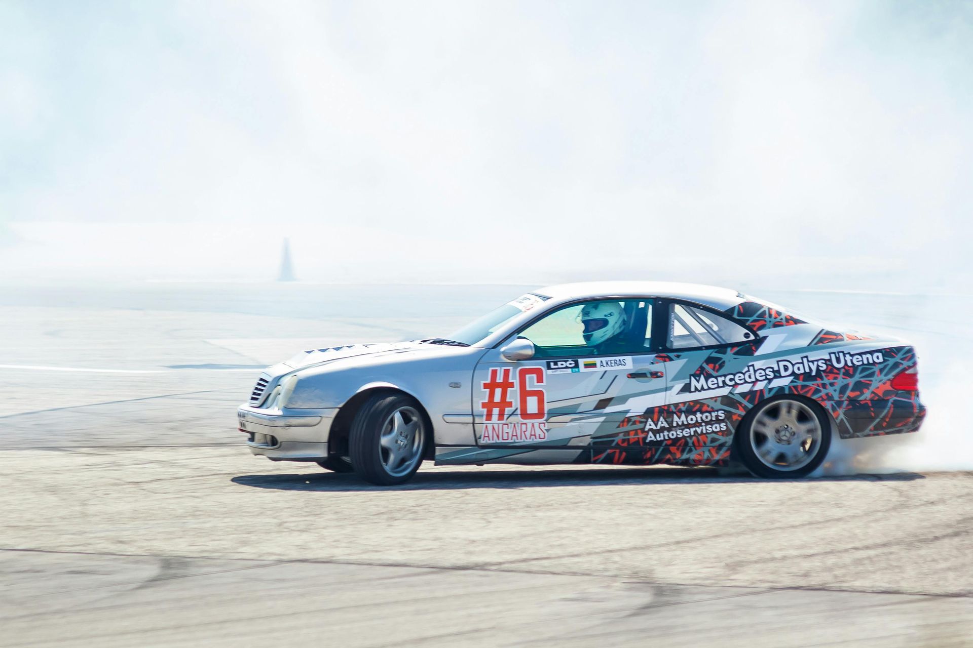 Silver race car #6 on a sandy beach with sea mist in the background
