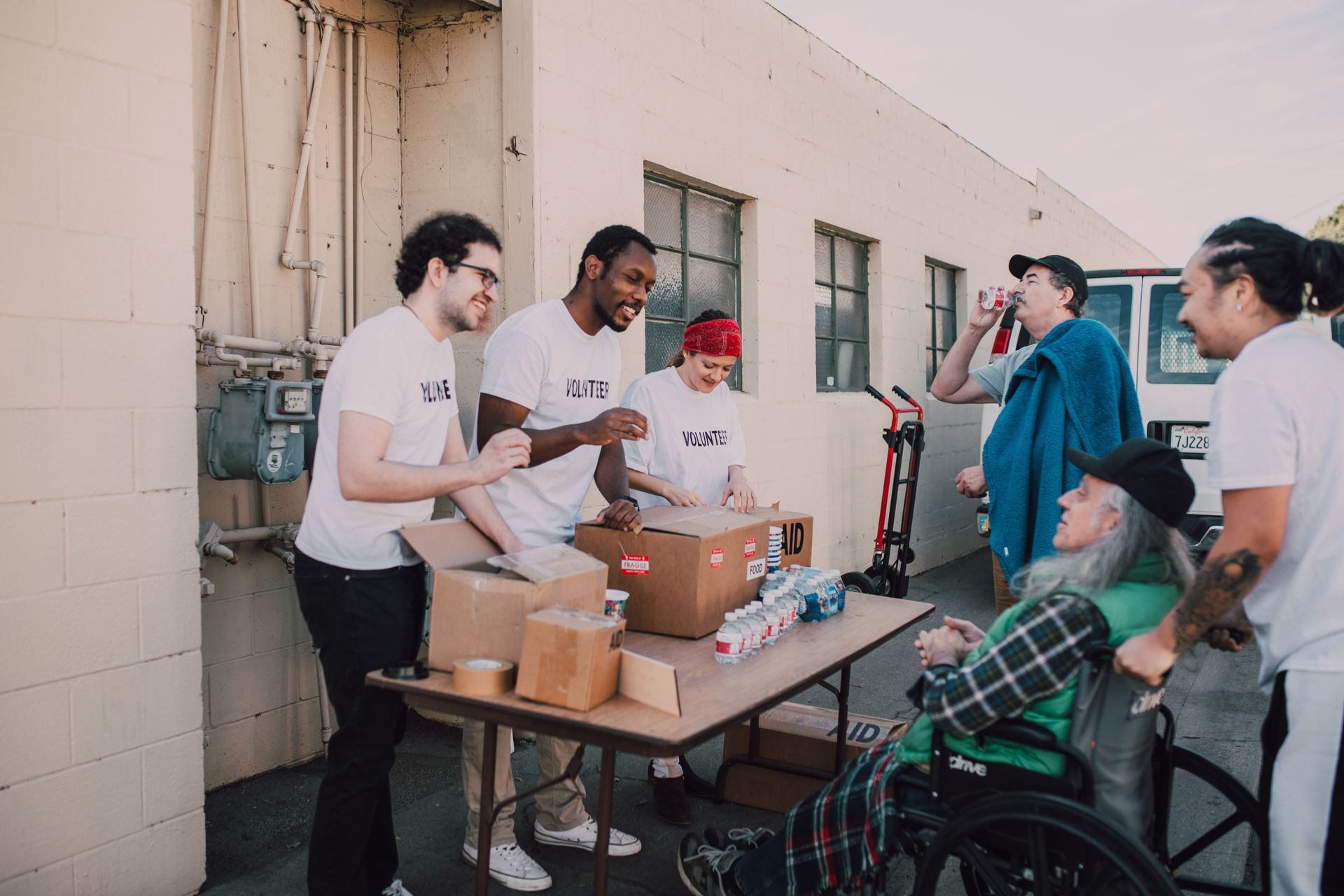 People handing out boxes at a table beside parked bicycles outside a building