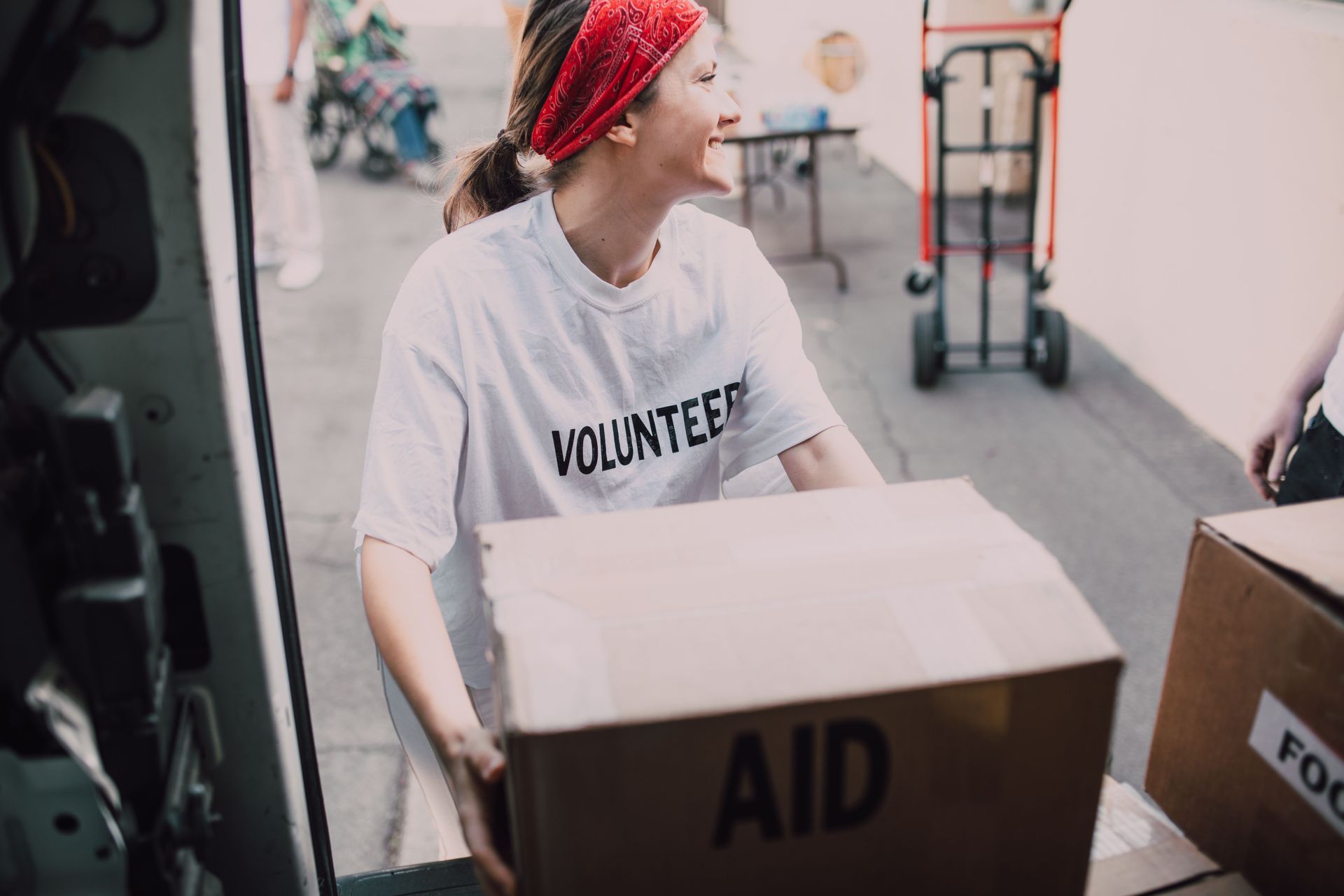 Volunteer in red bandana carrying an aid box at a relief center