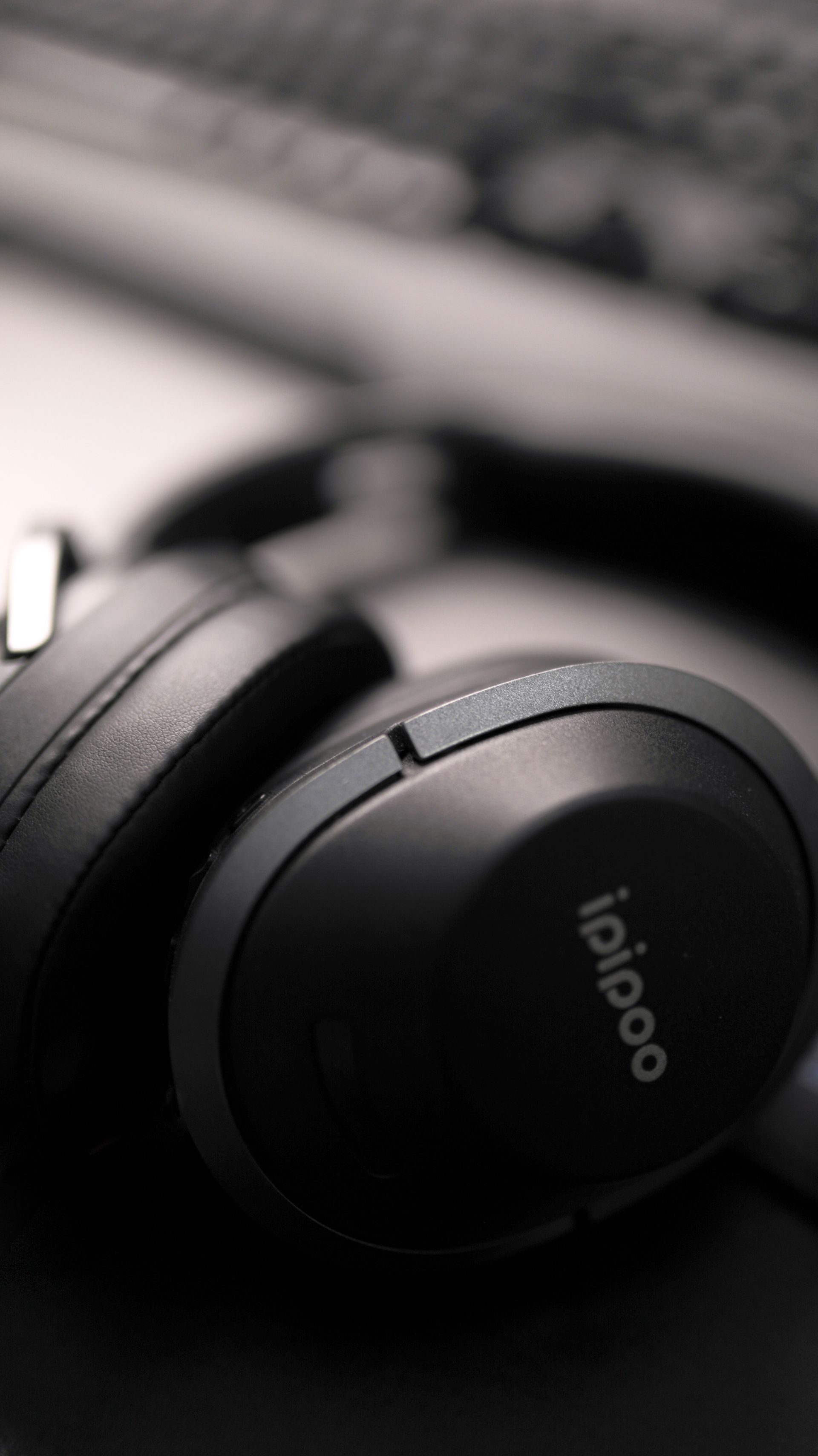 Close-up of black over-ear headphones resting on a desk near a keyboard