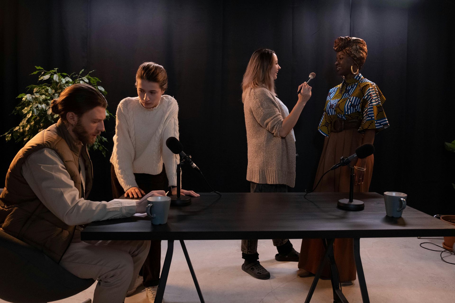 People working around a table in a studio, with microphones and a mannequin under warm lighting
