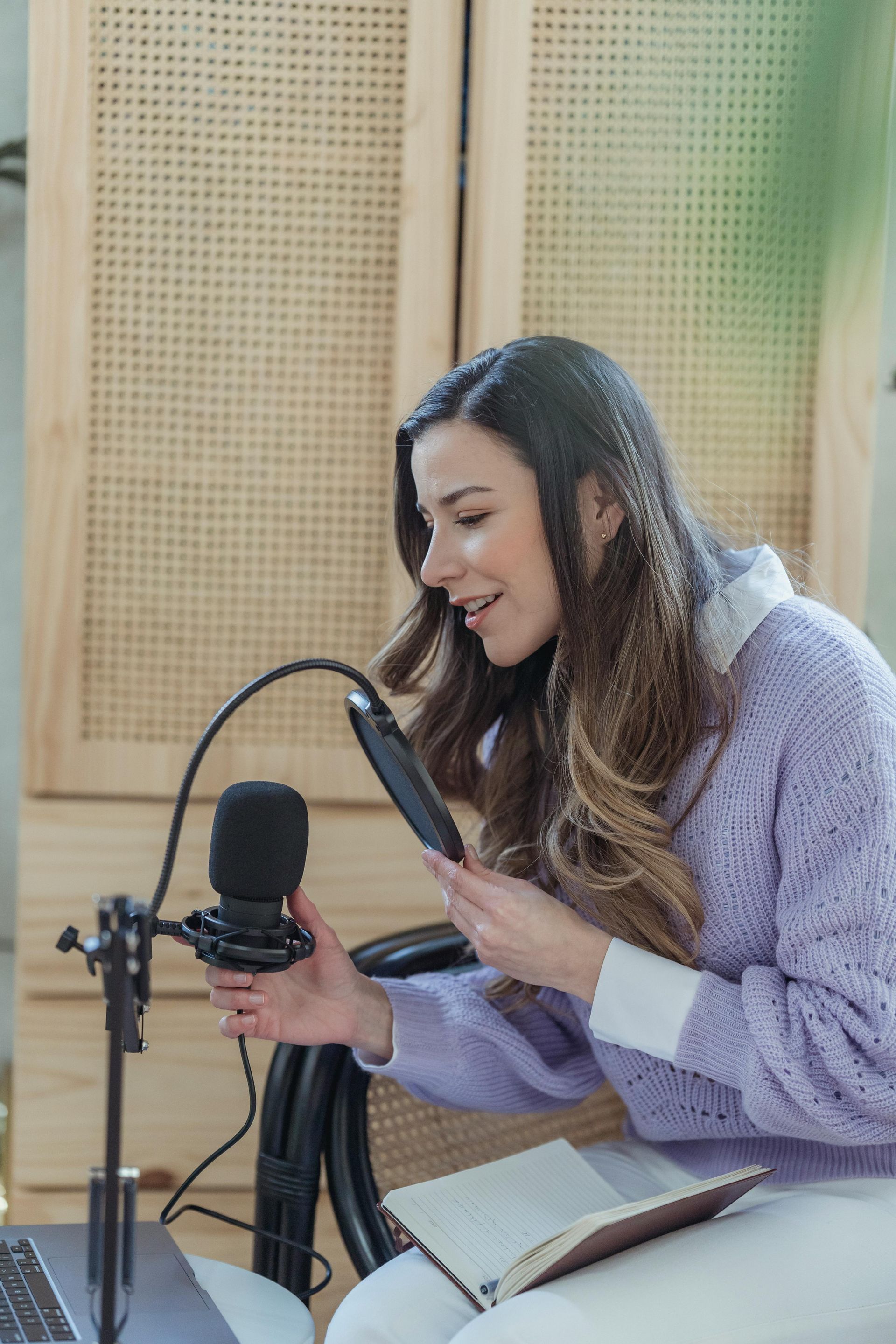 Woman speaking into a microphone while reading from a phone in a studio setting