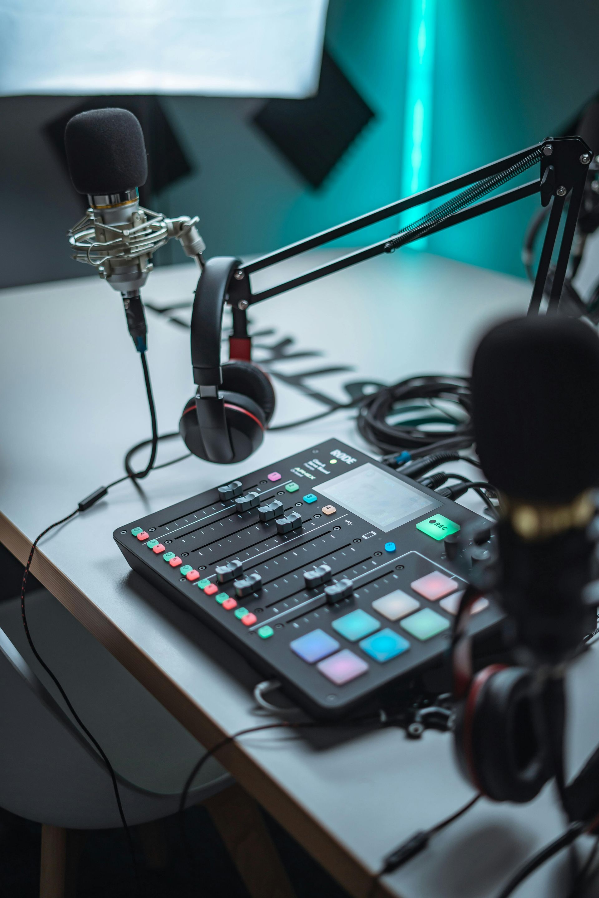 Podcast recording setup with microphone, headphones, and colorful audio mixer on a desk