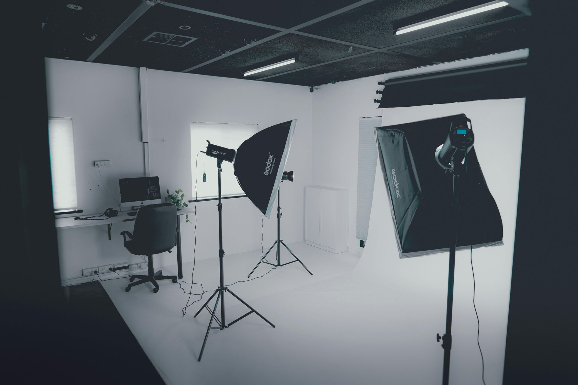 Photography studio with white backdrop, studio lights, and camera equipment on stands