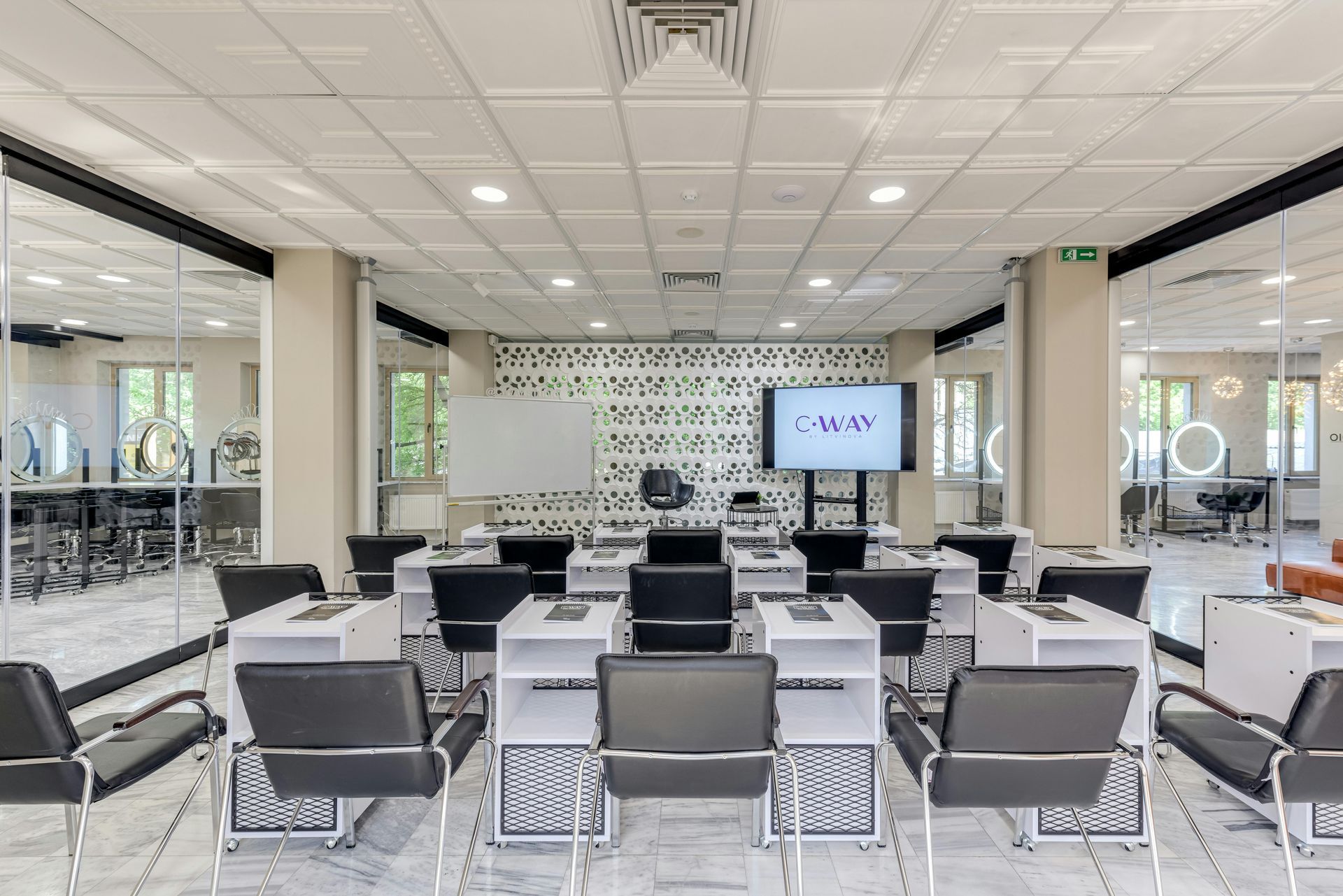 Modern conference room with rows of black chairs facing a presentation screen and whiteboard