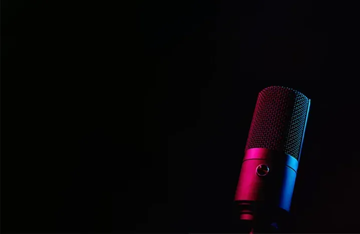 Black microphone lit with pink and blue light against a dark background
