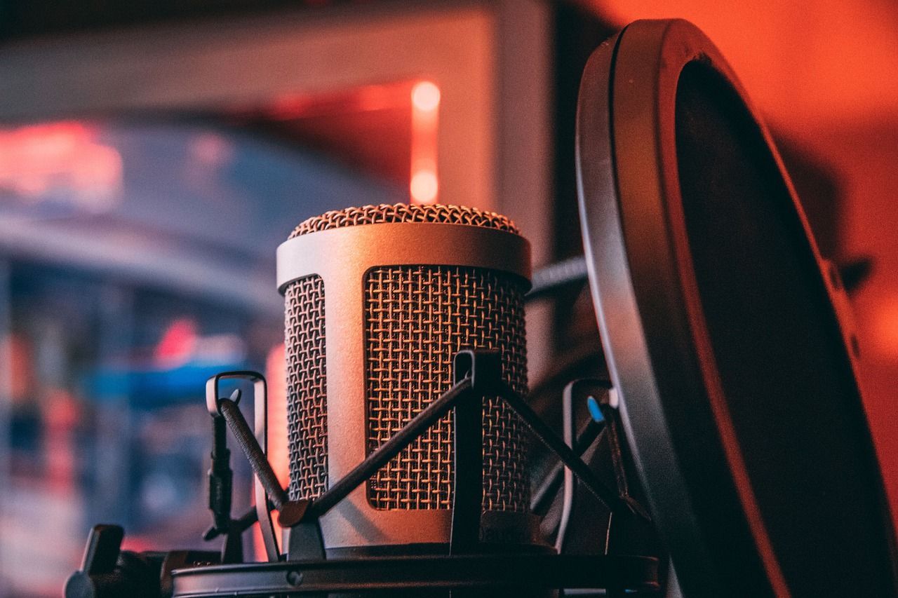 Close-up of a studio microphone with a pop filter in warm red lighting