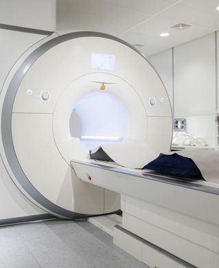 Uma grande máquina de ressonância magnética branca está em um quarto de hospital.