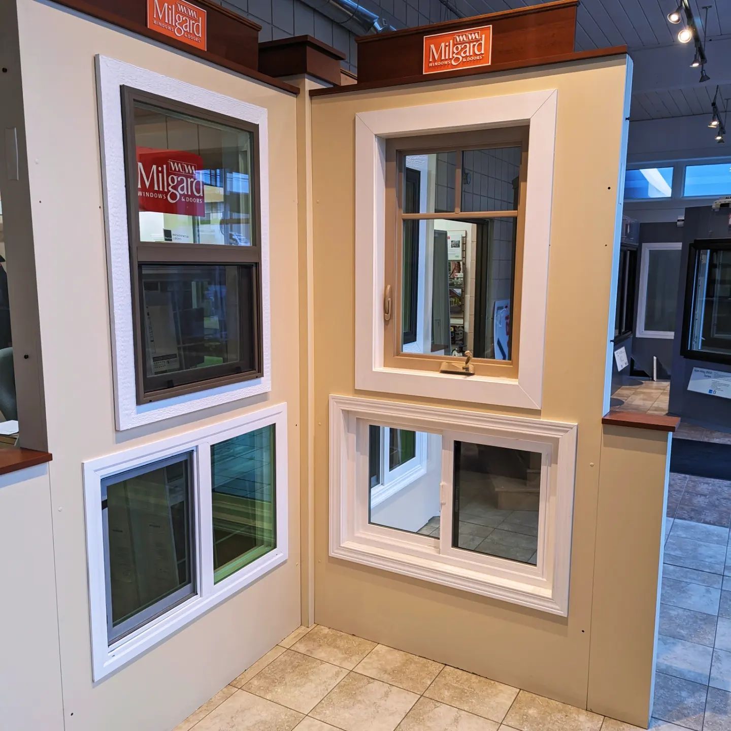 Showroom display featuring three windows of different sizes with white frames mounted on beige panels.