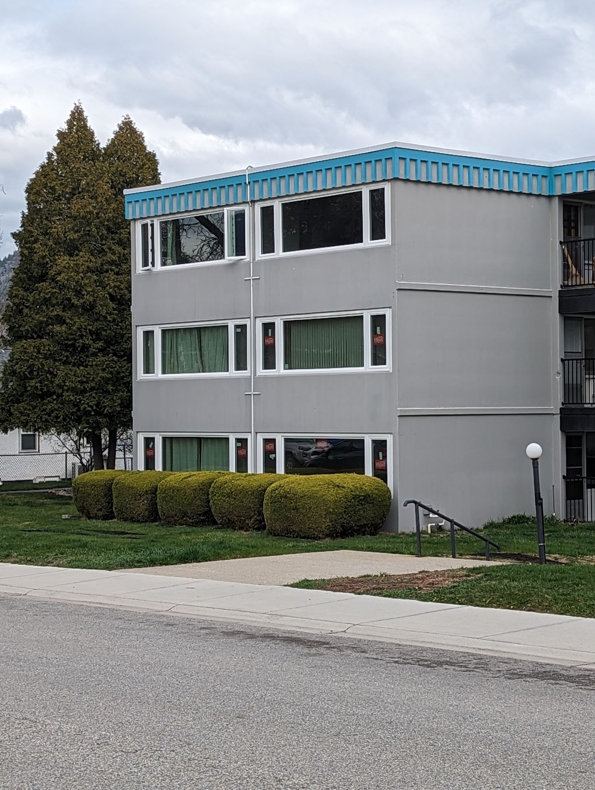 Modern three-story residential building with white windows and turquoise blue roof.
