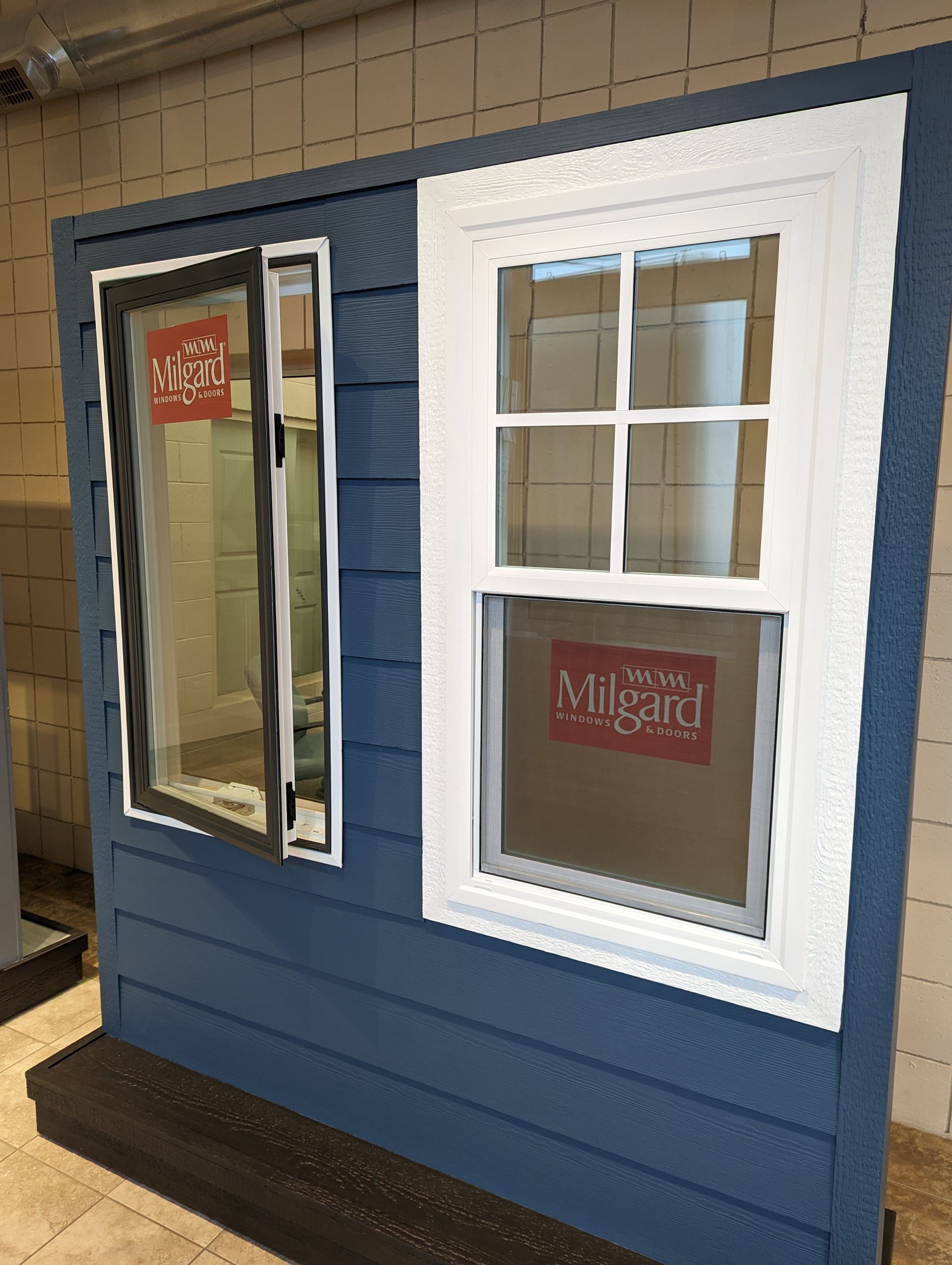 Exhibition display showing a white entry door with windows and a glass sidelite, installed in a showroom.