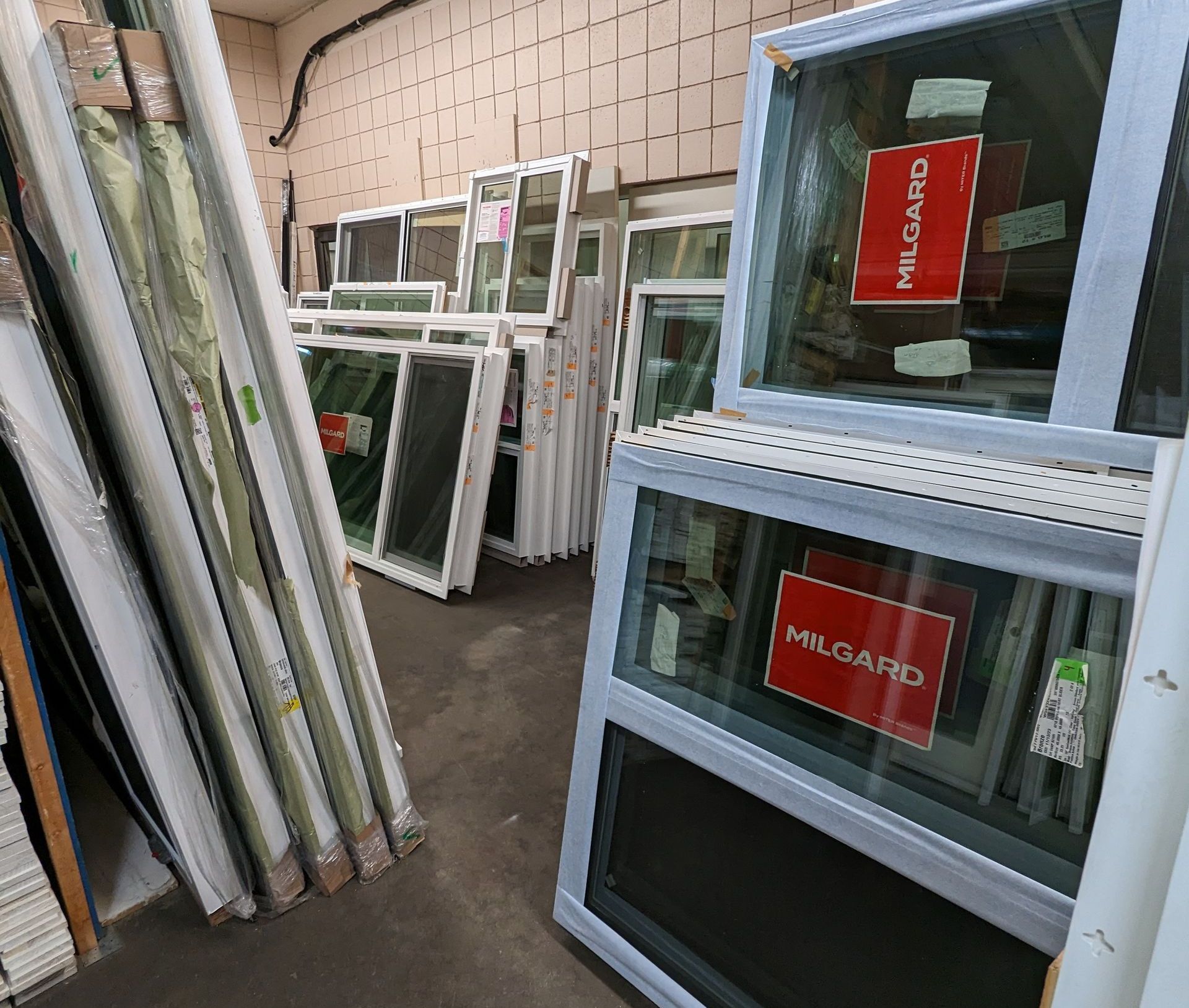Warehouse interior with stacks of new white Milgard windows for sale.