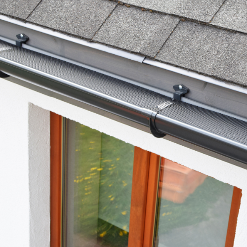 A close up of a gutter on a roof next to a window