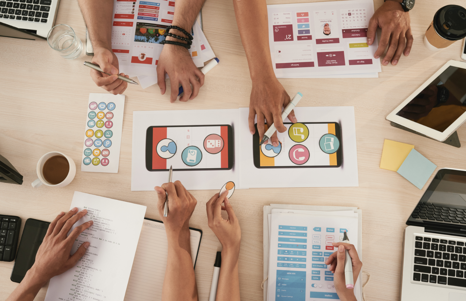 Team collaboration around laptops and printed charts on a wooden desk during a meeting
