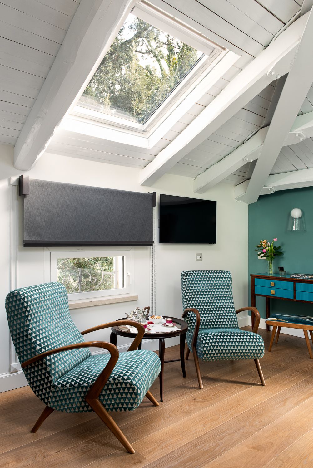 Living room with skylight, patterned armchairs, and wood beams.