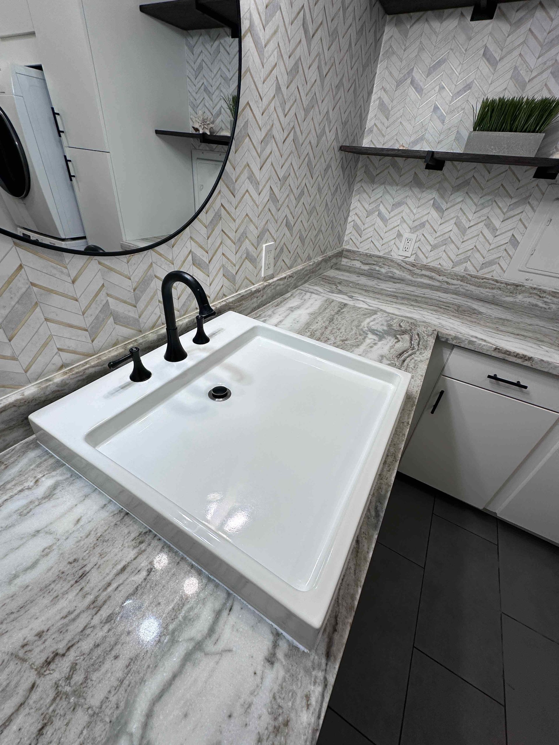 Modern bathroom vanity with white sink, black faucet, marble countertop, mirror, and hex tile walls