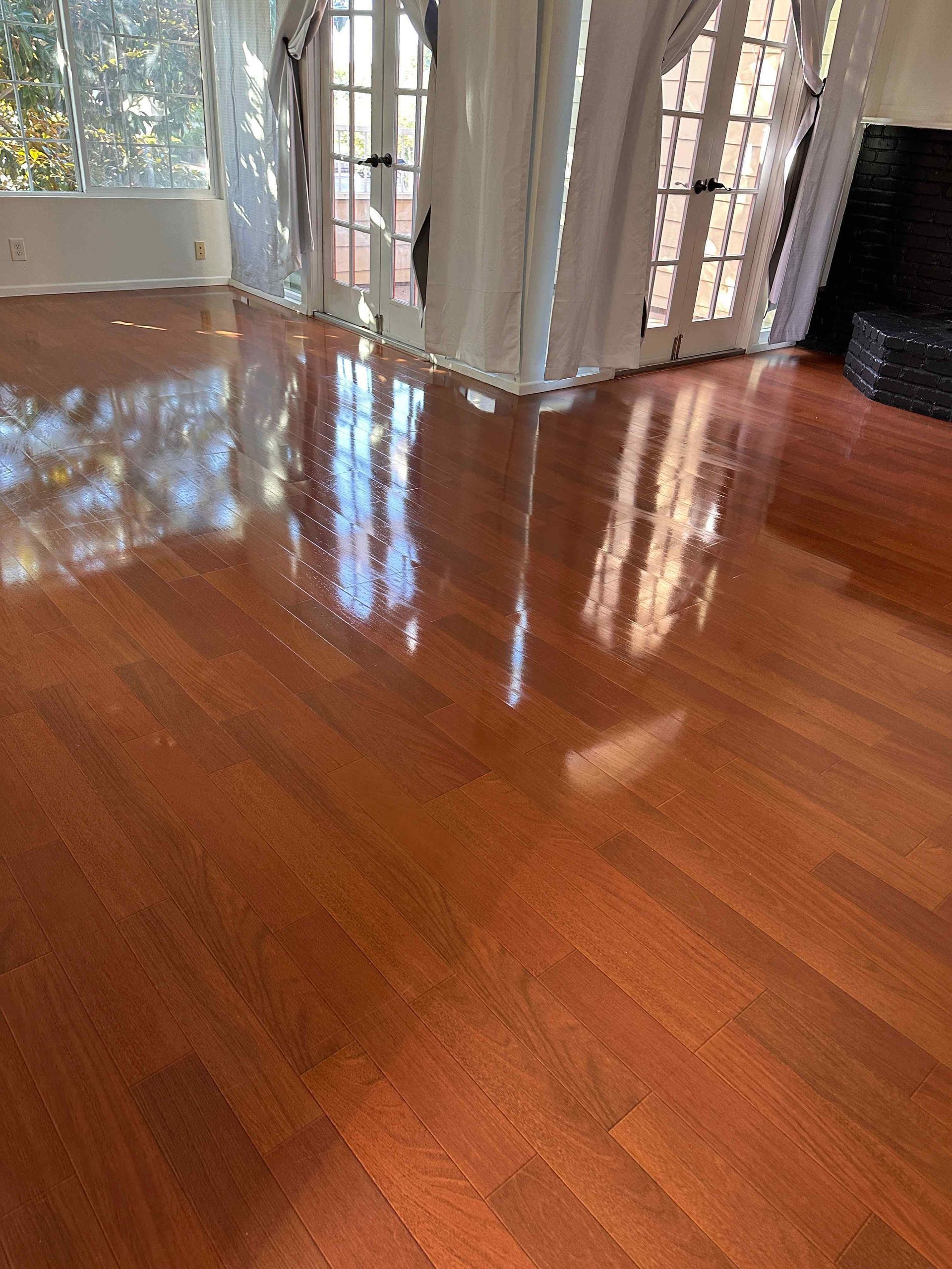 Sunlit hardwood floor reflecting curtains and window light in a room