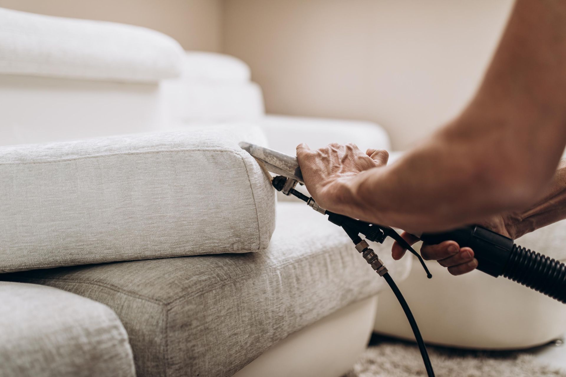 A team in uniforms cleans a bright living room, including washing windows, dusting, vacuuming, and wiping furniture.