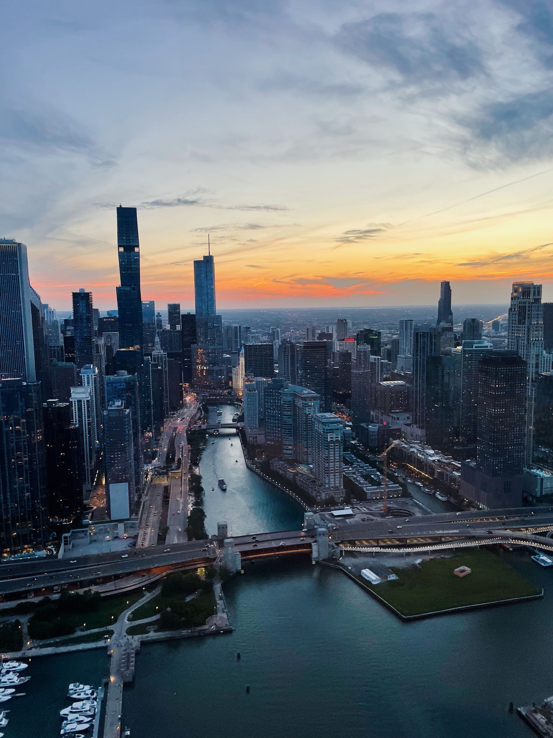 City skyline at sunset, river flowing through buildings, colorful sky, bridges.