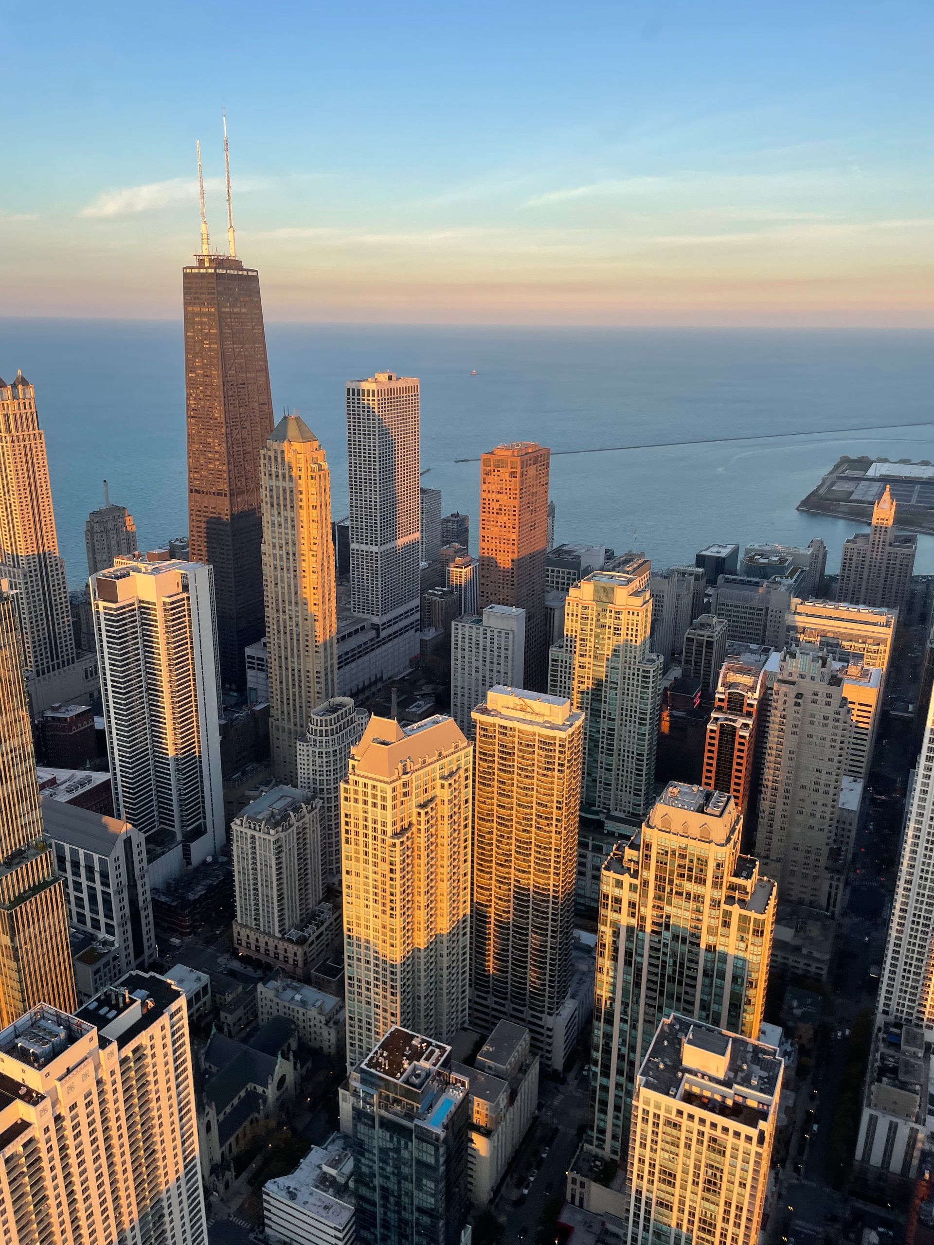 Chicago skyline at sunset with golden light on buildings, Lake Michigan in background.