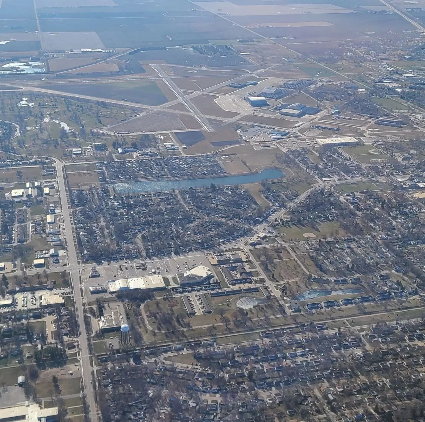 Aerial view of a town with an airport, roads, buildings, and a lake.