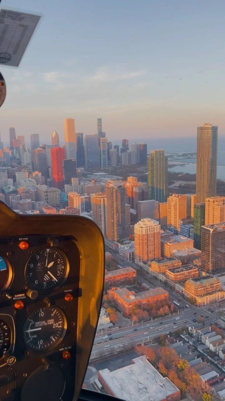 Helicopter view of Chicago skyline at sunset, golden light illuminating buildings.