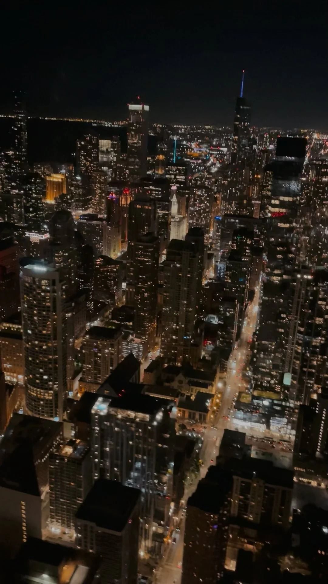 Nighttime aerial view of a brightly lit city skyline, with skyscrapers and streets.