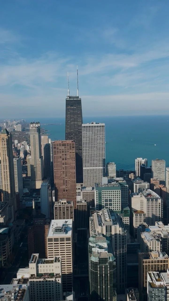 Aerial view of Chicago skyline with skyscrapers against a blue sky and Lake Michigan.