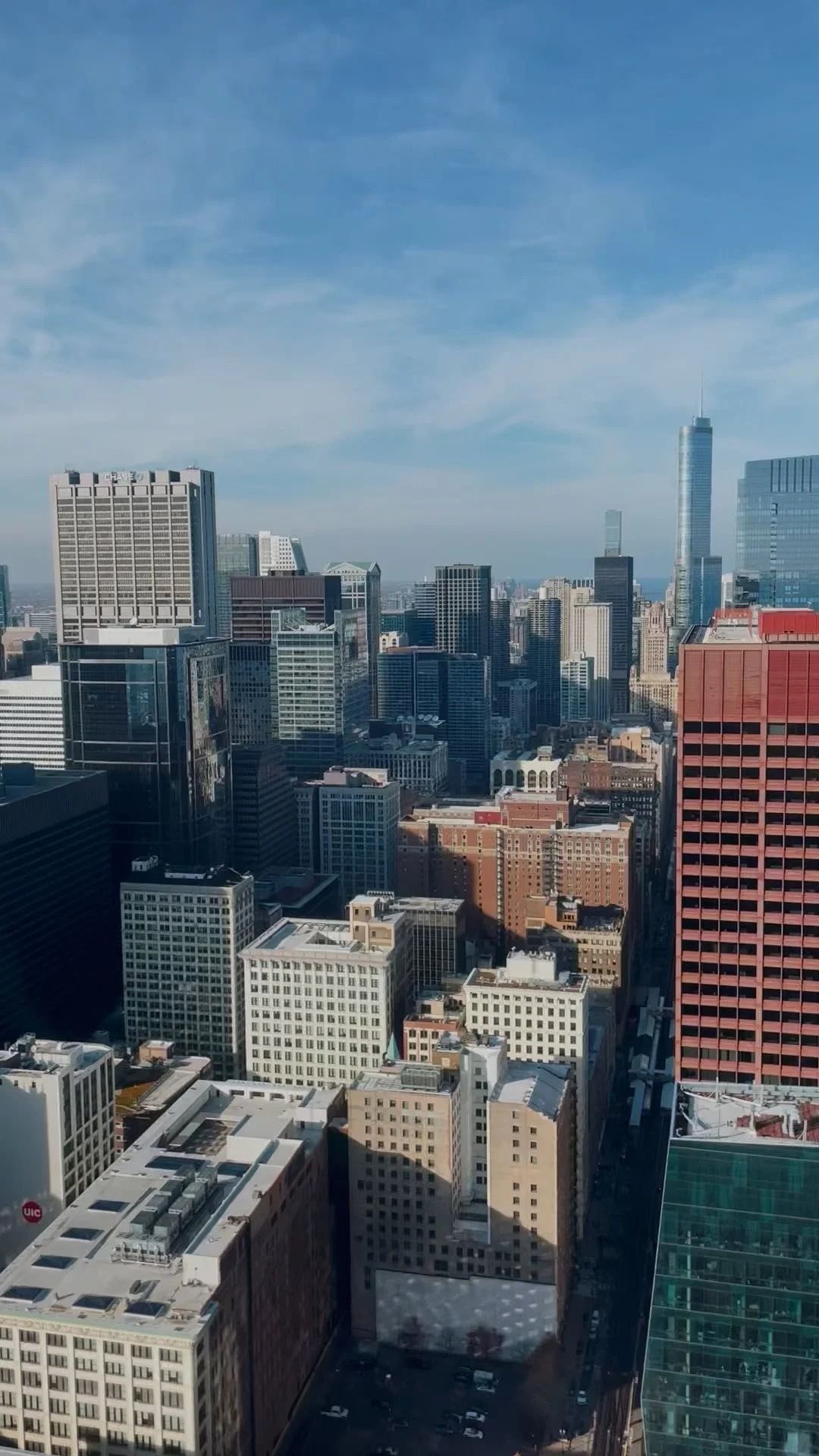 Cityscape with tall buildings under a blue sky, with the One World Trade Center in the distance.