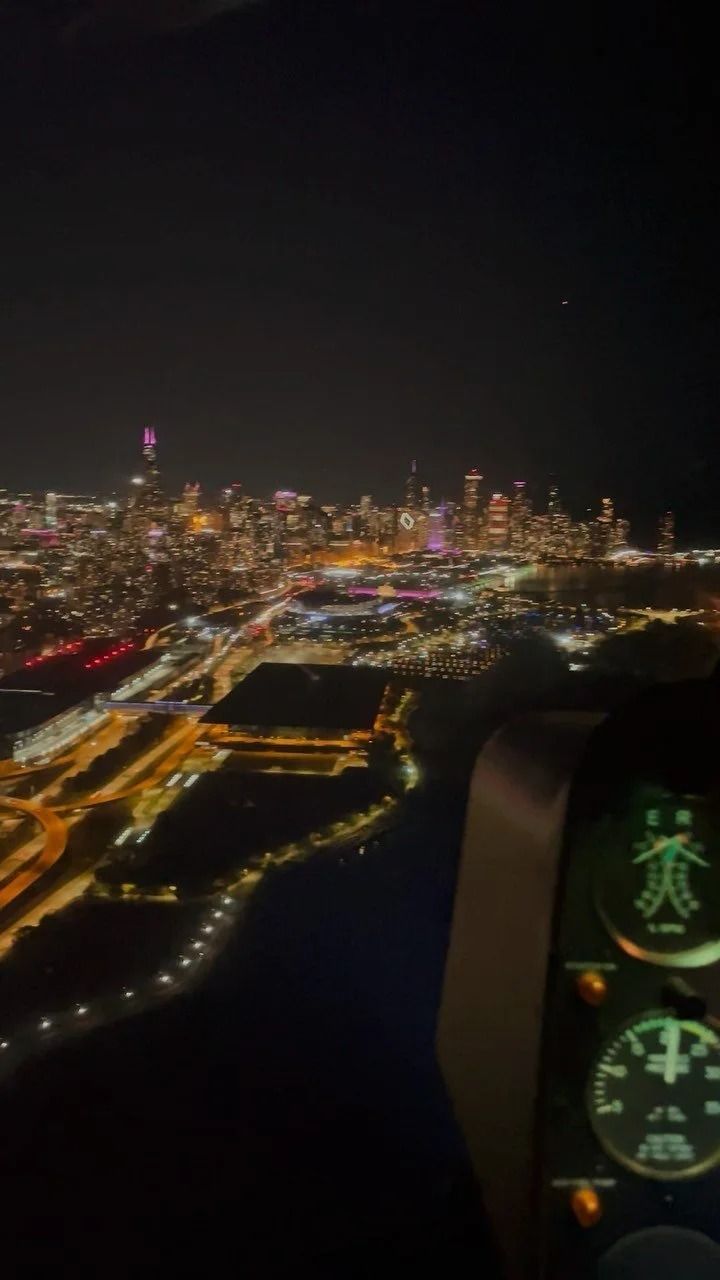 Night view from cockpit of city skyline with glowing lights.