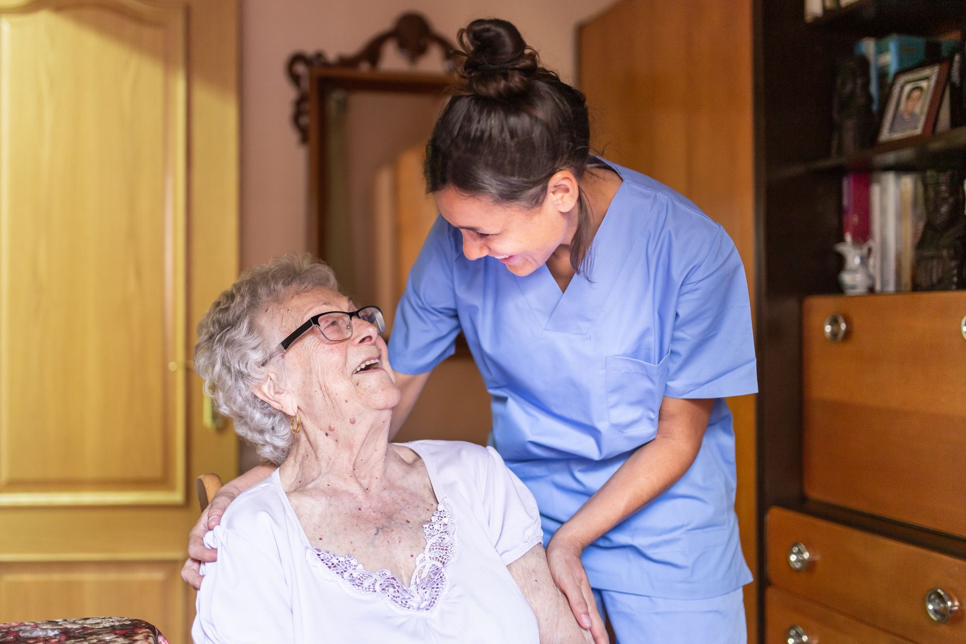 Senior woman laughing with her caregiver during in-home care visit