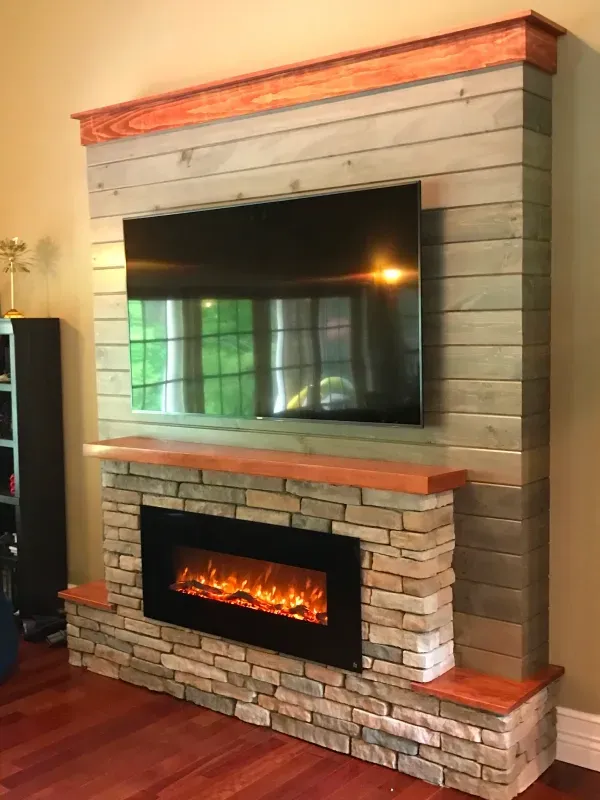 Fireplace with stacked stone and faux wood, electric fire, TV above.