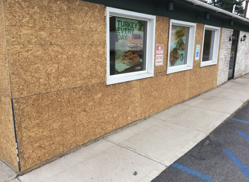 Exterior view of a restaurant with a boarded-up facade and windows.