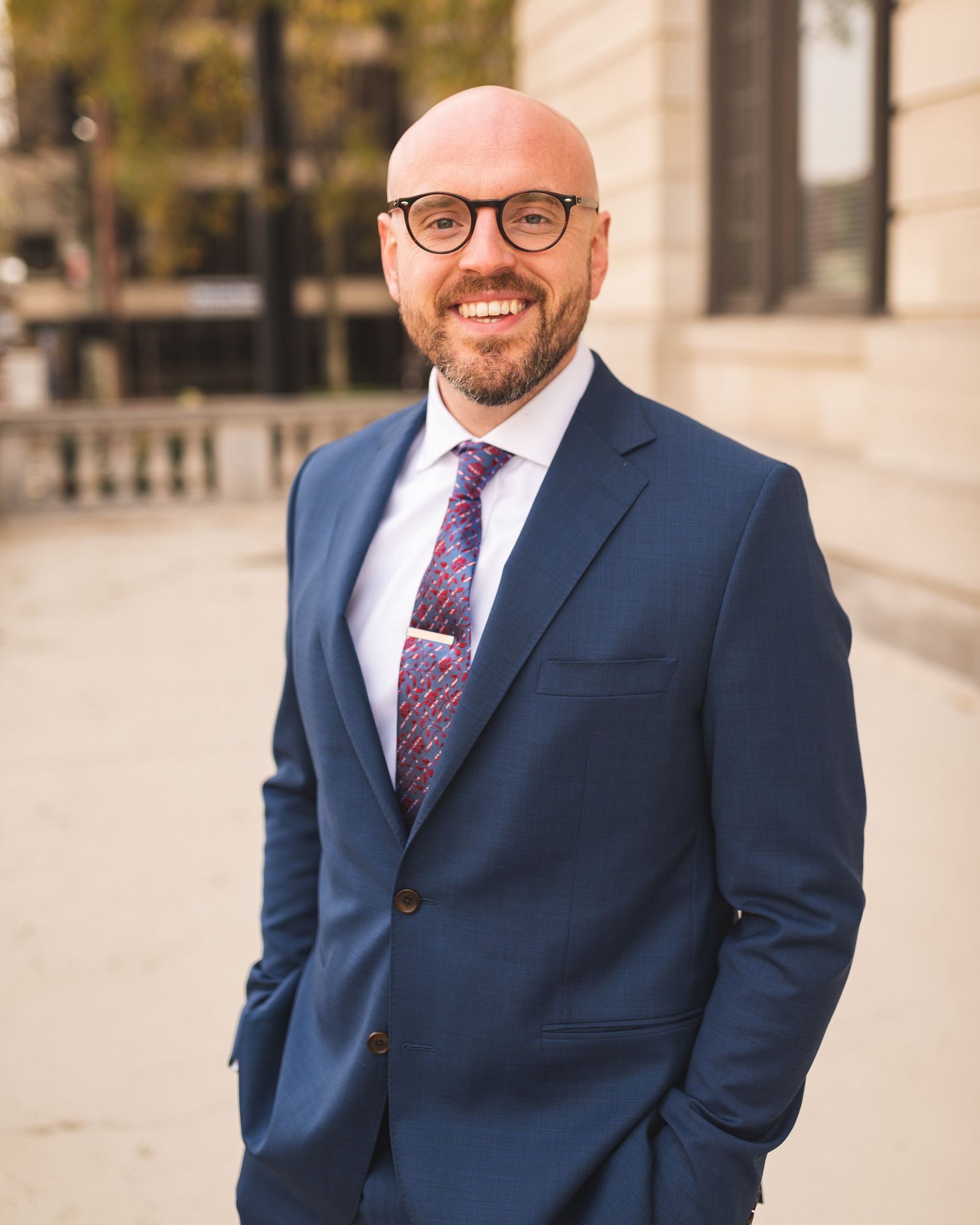 A man in a suit and tie is standing in front of a building.