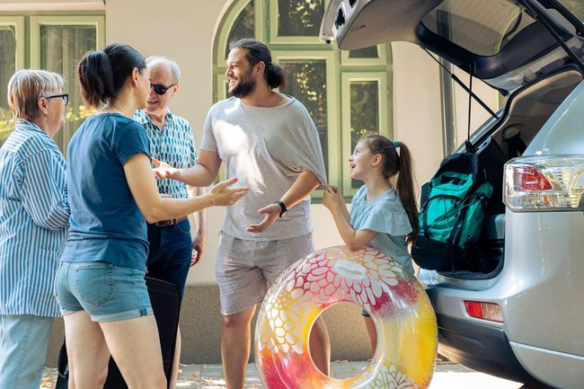 A group of people are standing around a car with a life preserver in the back.