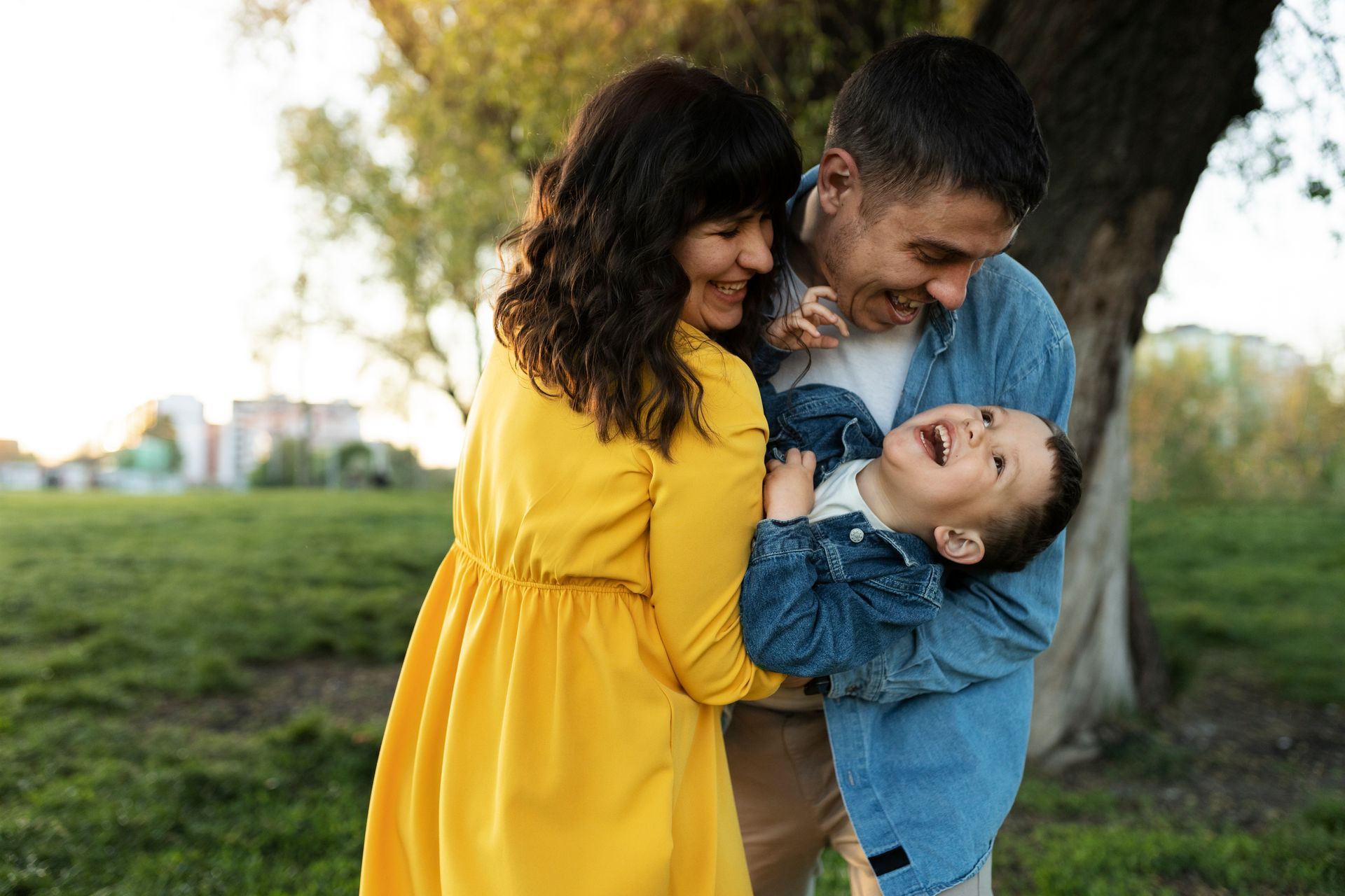 A man and woman are holding a child in their arms in a park.