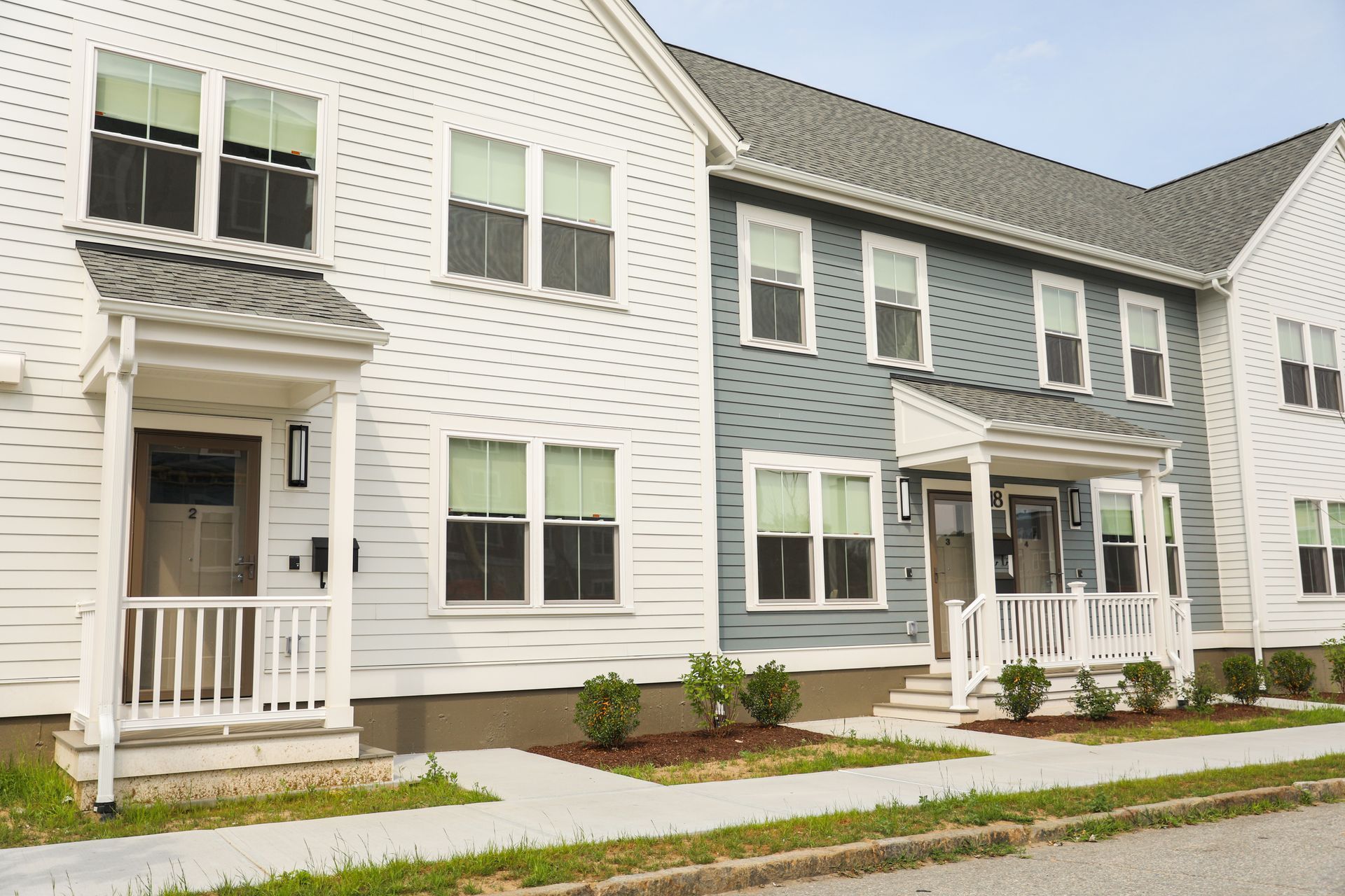 A row of white and blue houses with a white porch.