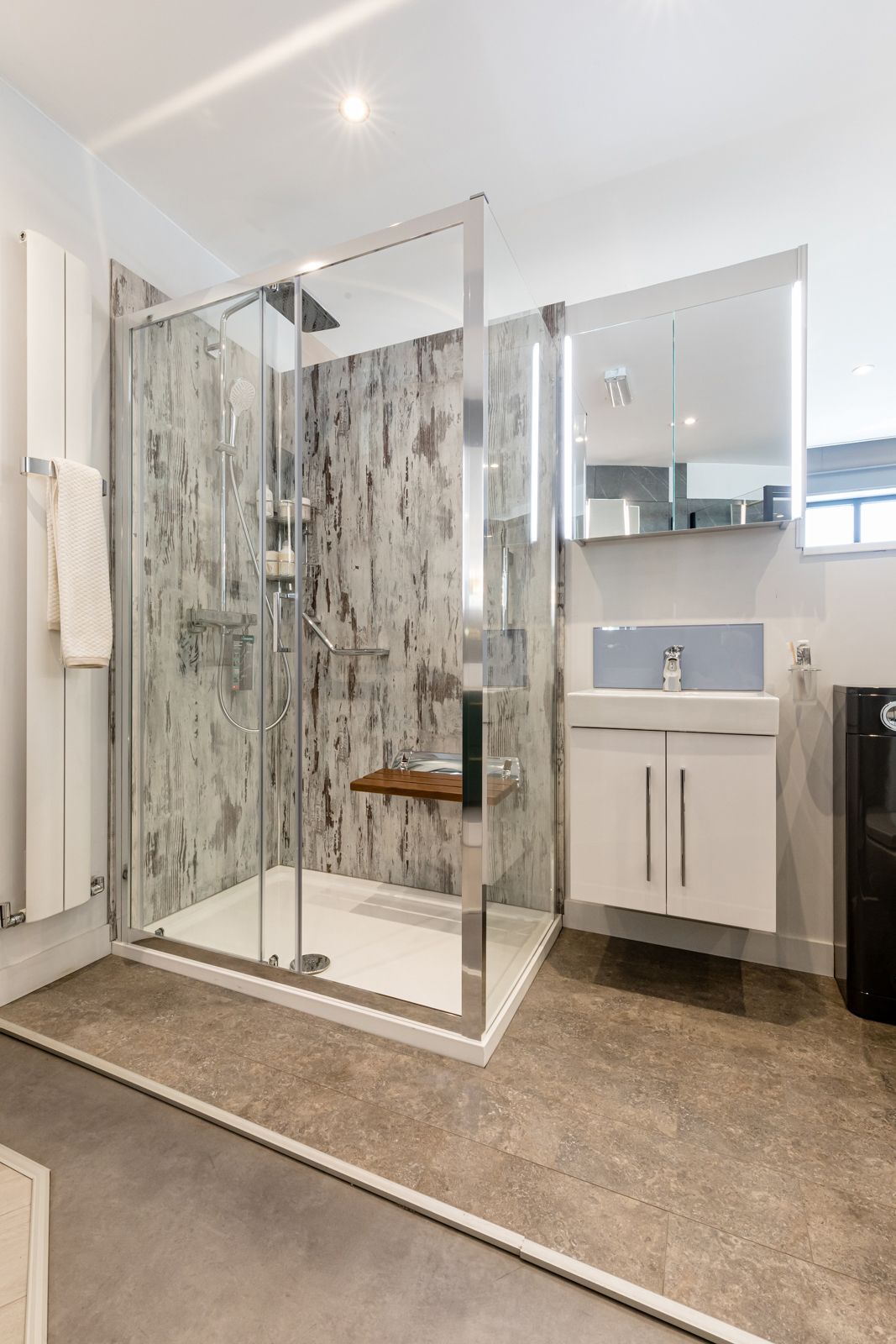 A bathroom with a walk in shower , sink and mirror.