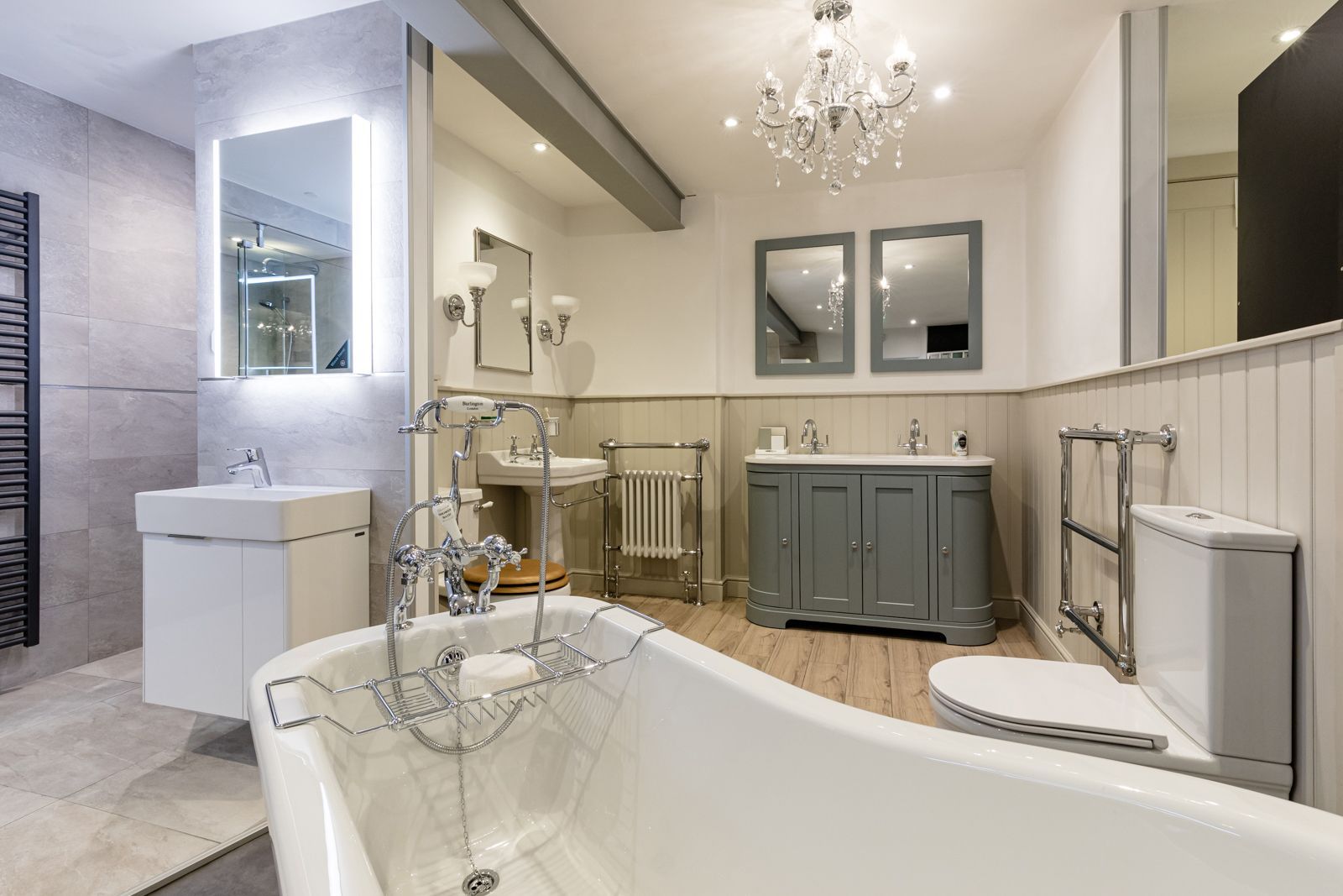 A bathroom with a bathtub , sink , toilet and mirrors.