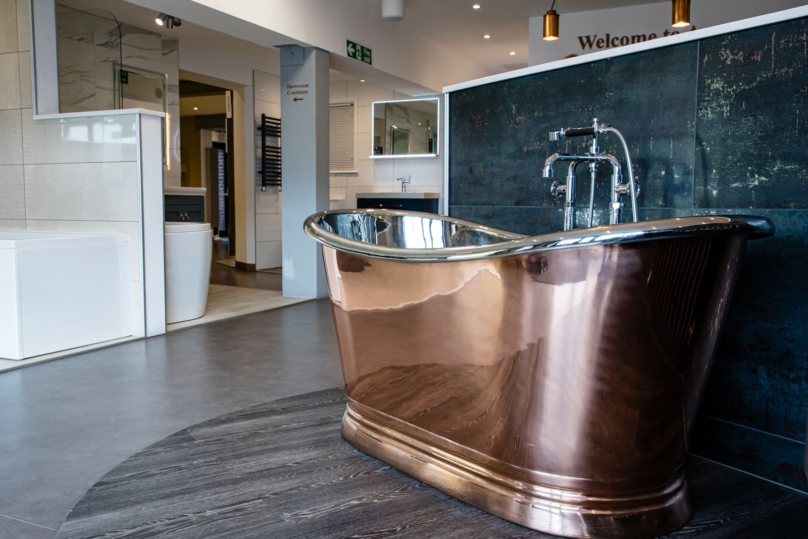 A copper bathtub is sitting on the floor in a bathroom showroom.